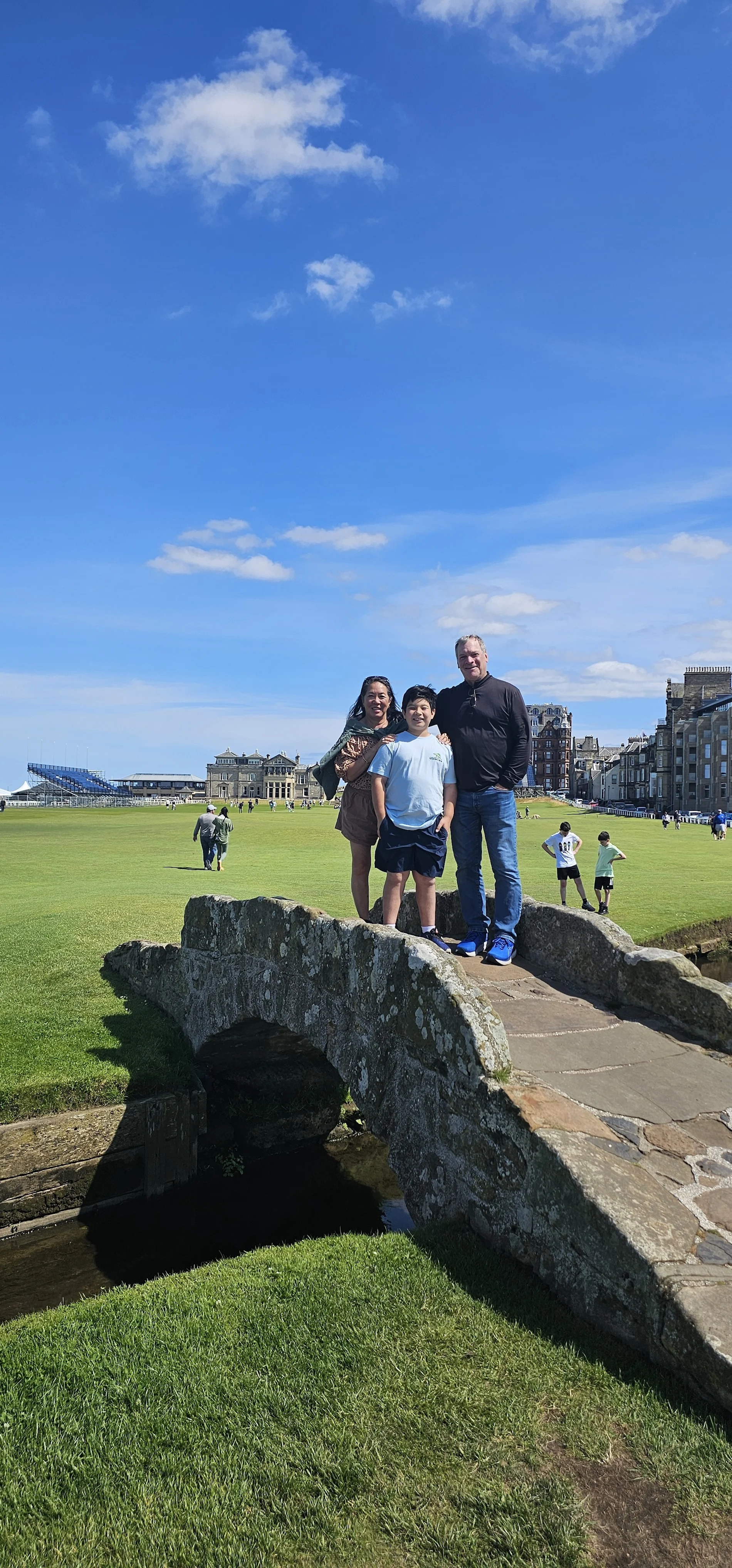 Family standing on historic stone bridge at St Andrews Golf Course, Scotland