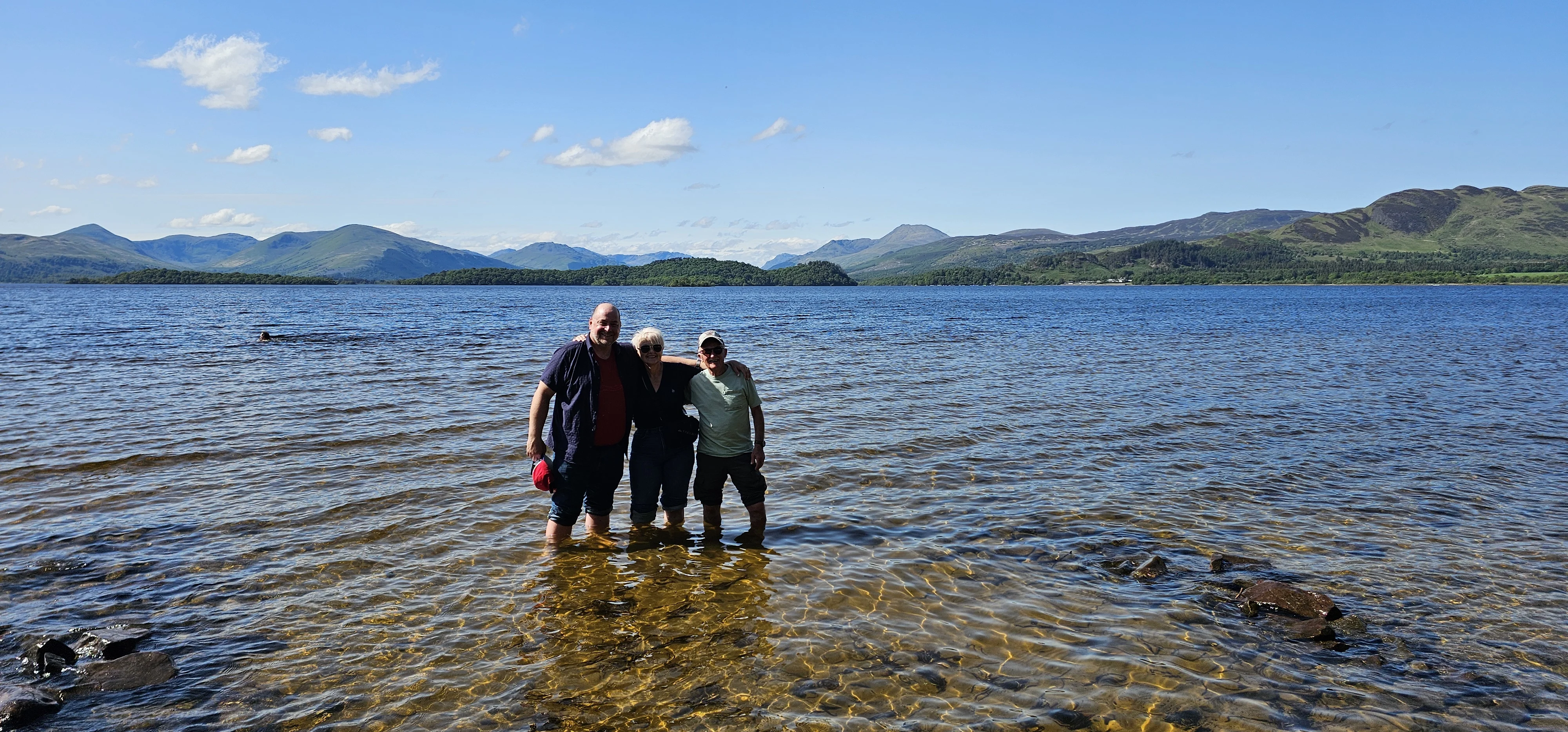 Family wading in Scottish loch with mountains in background