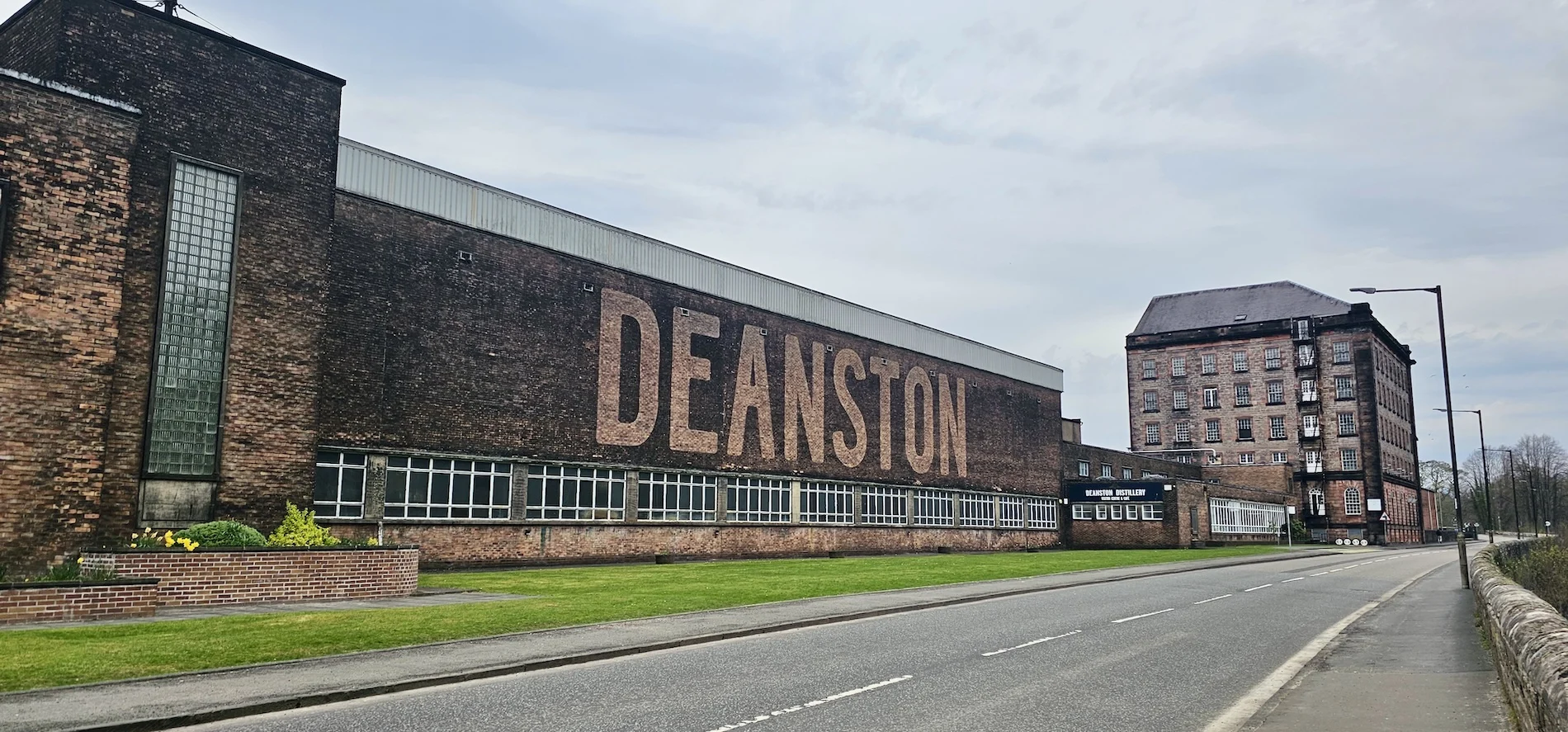 Historic Deanston Distillery building with large signage and brick architecture