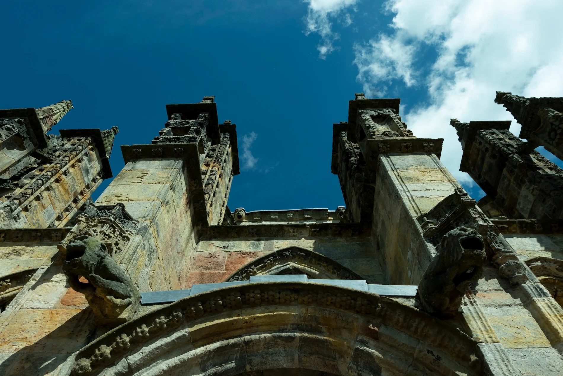 Upward view of ruined Scottish castle towers against blue sky