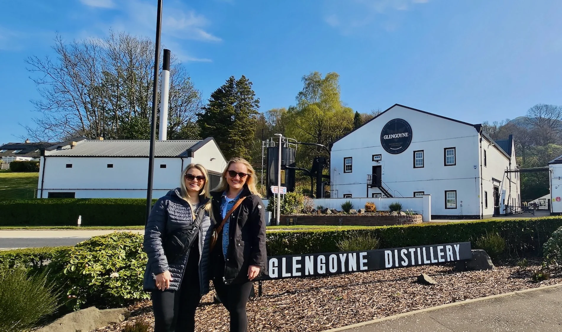 Two women posing at Glengoyne Distillery entrance on Scottish tour