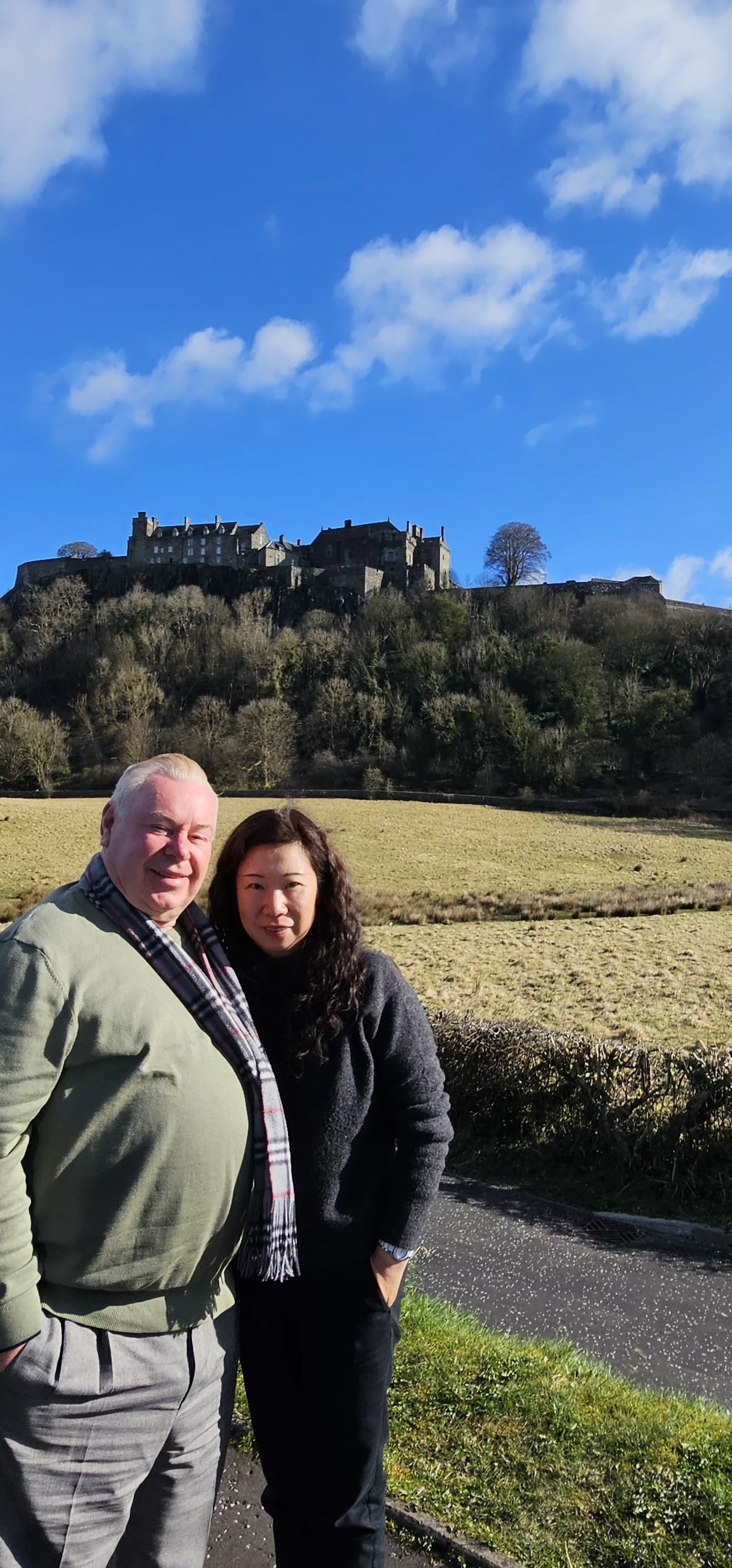 Two tourists posing in front of Edinburgh Castle on a Scottish day tour.