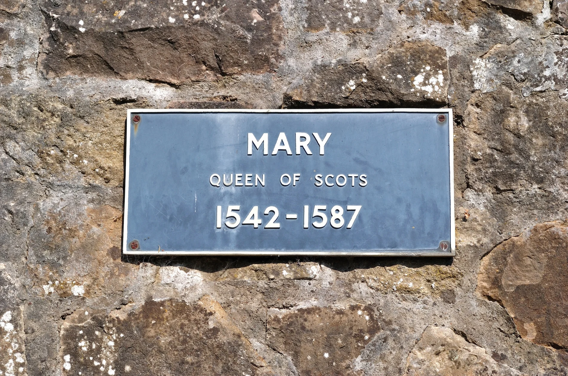 Blue plaque commemorating Mary Queen of Scots on weathered stone wall.