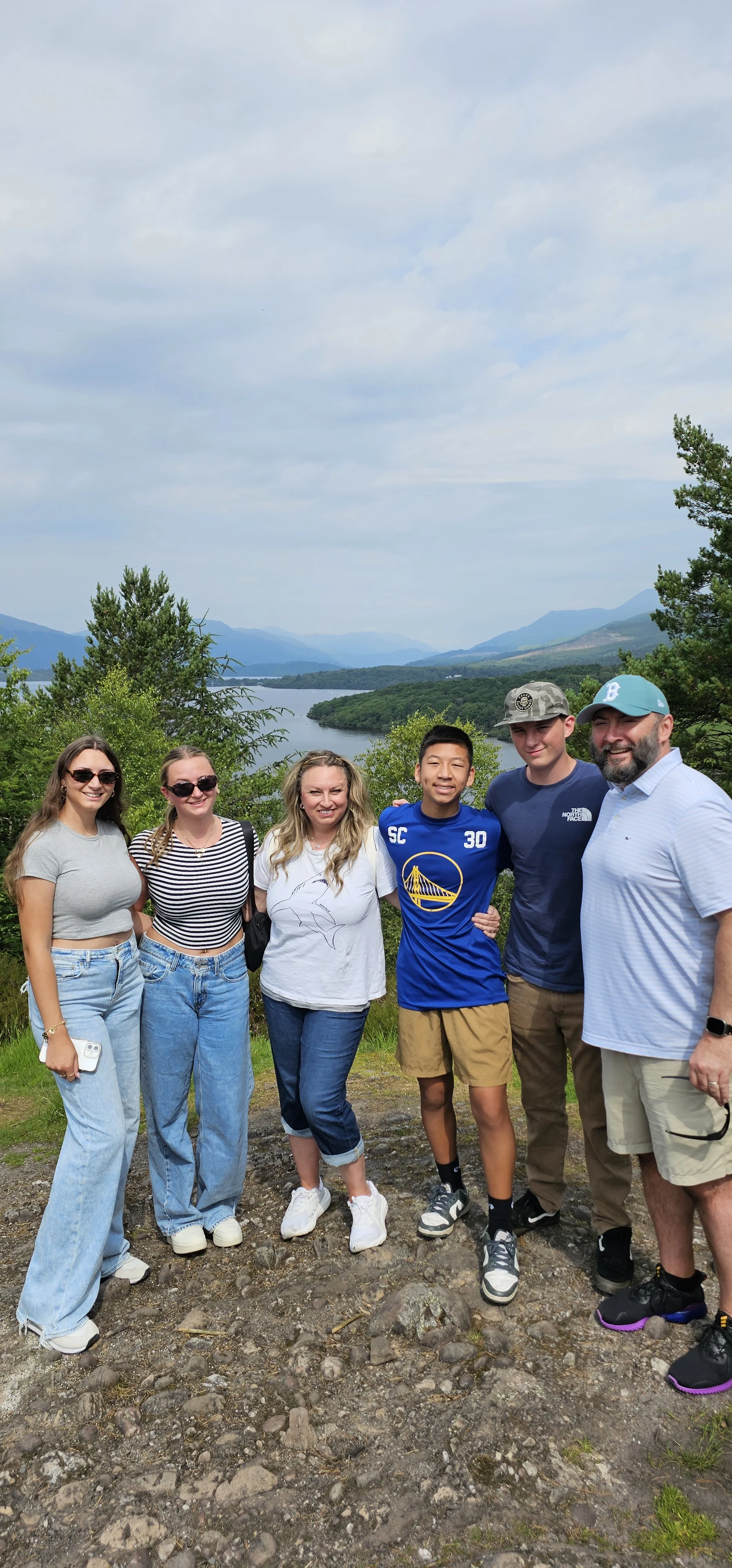 Group of six people posing together overlooking a Scottish loch and mountains