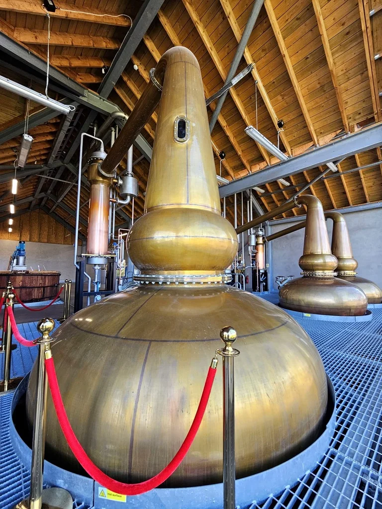 Large copper whisky stills in a Scottish distillery interior