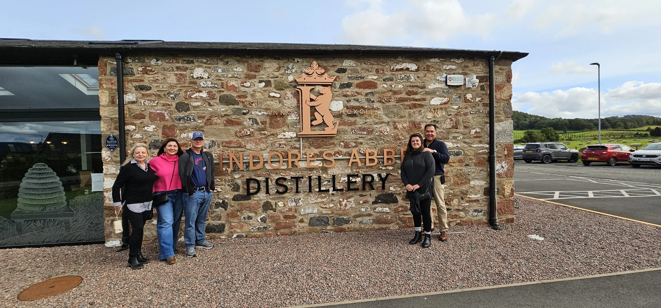 Tourists posing at Lindores Abbey Distillery sign in Scotland