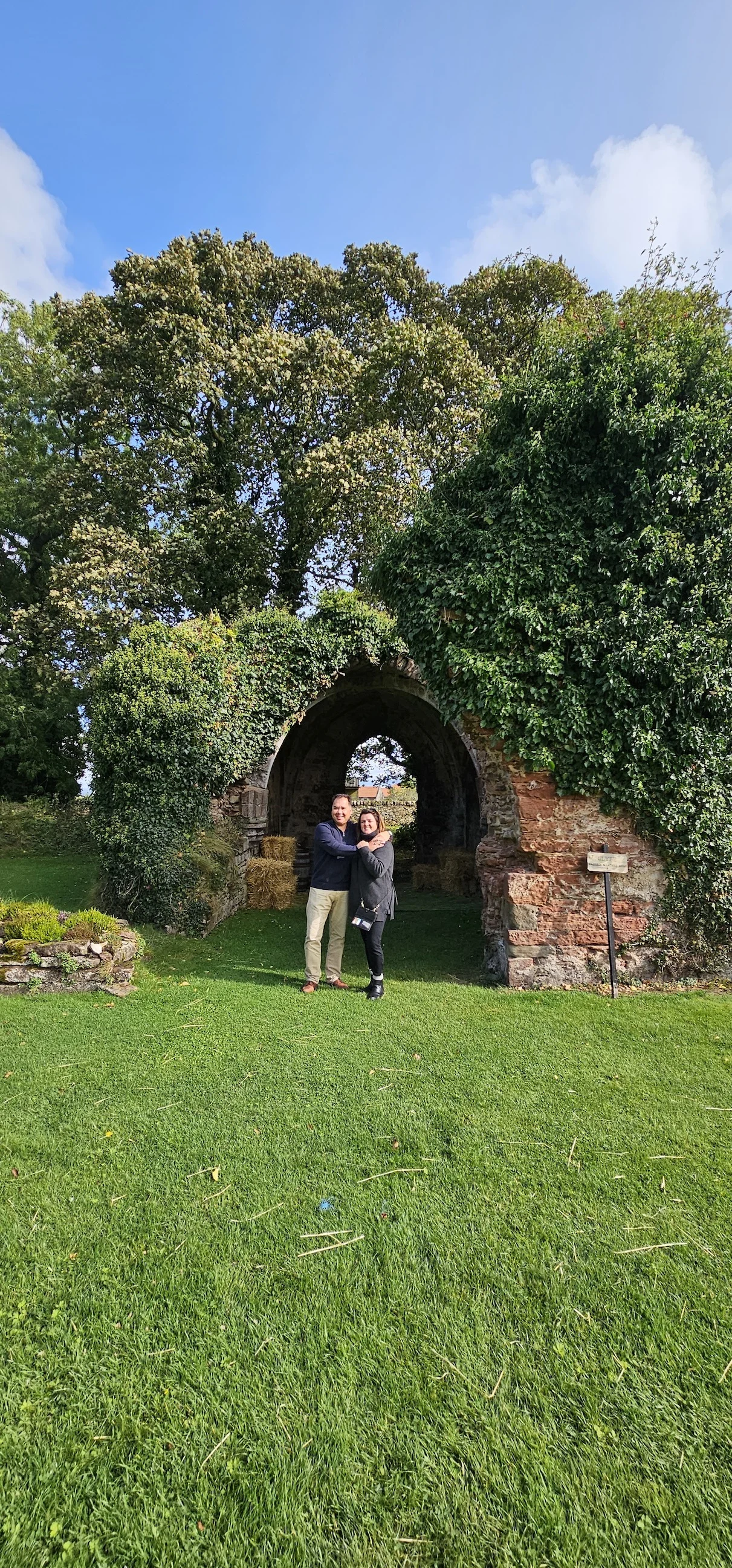 Couple posing at ivy-covered stone archway in Scottish countryside
