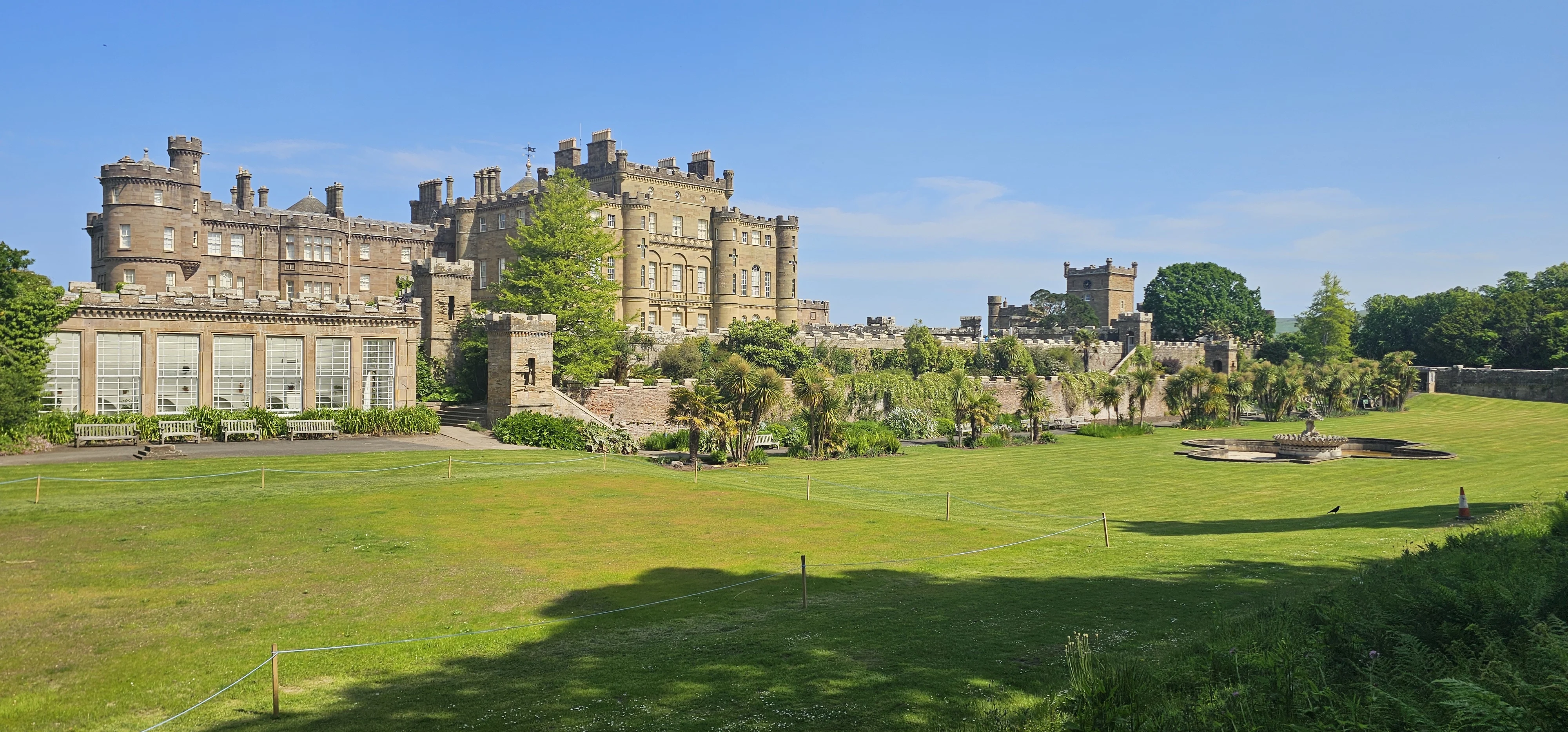 Scottish castle with manicured grounds and palm trees on sunny day