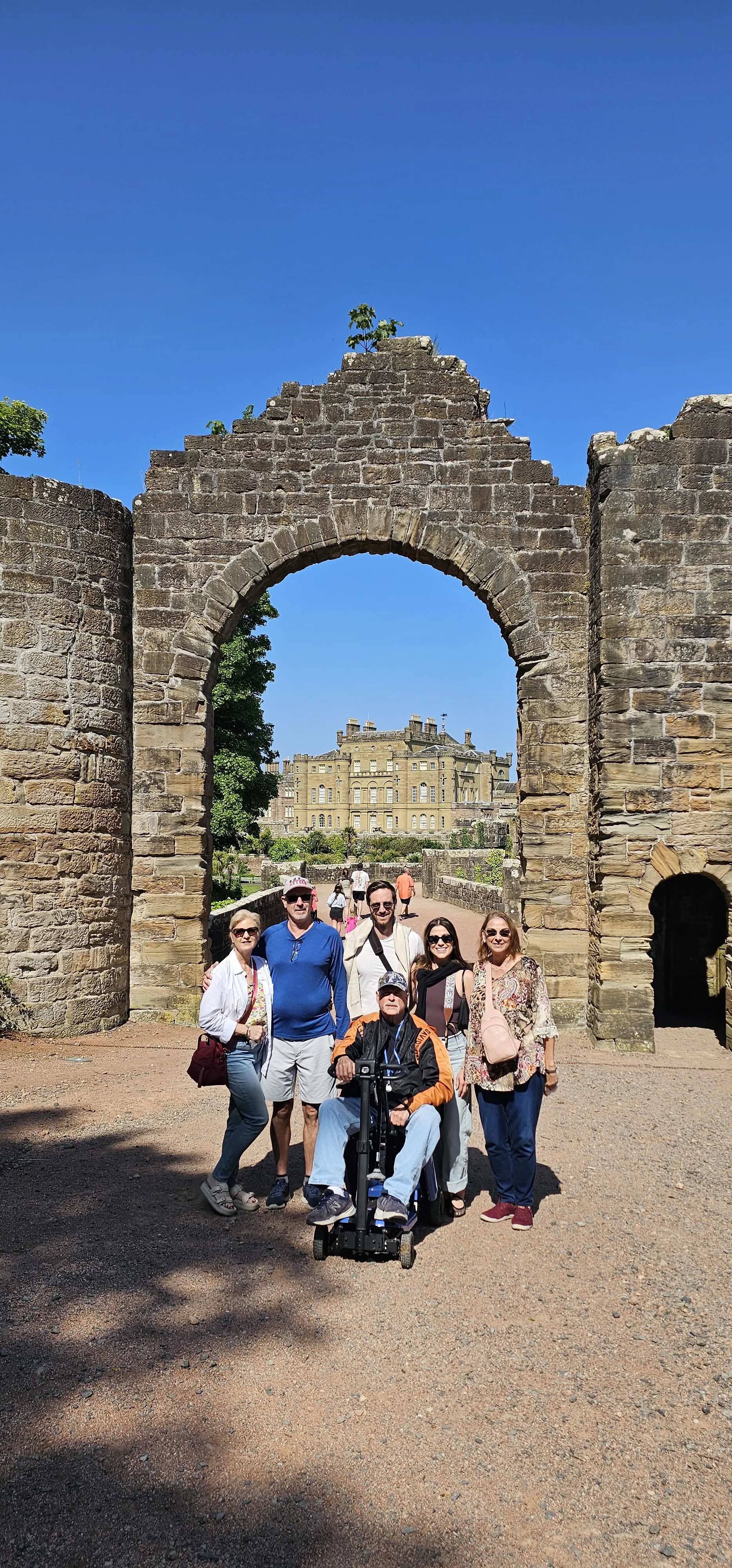 Tour group posing at historic Scottish castle stone archway ruins.
