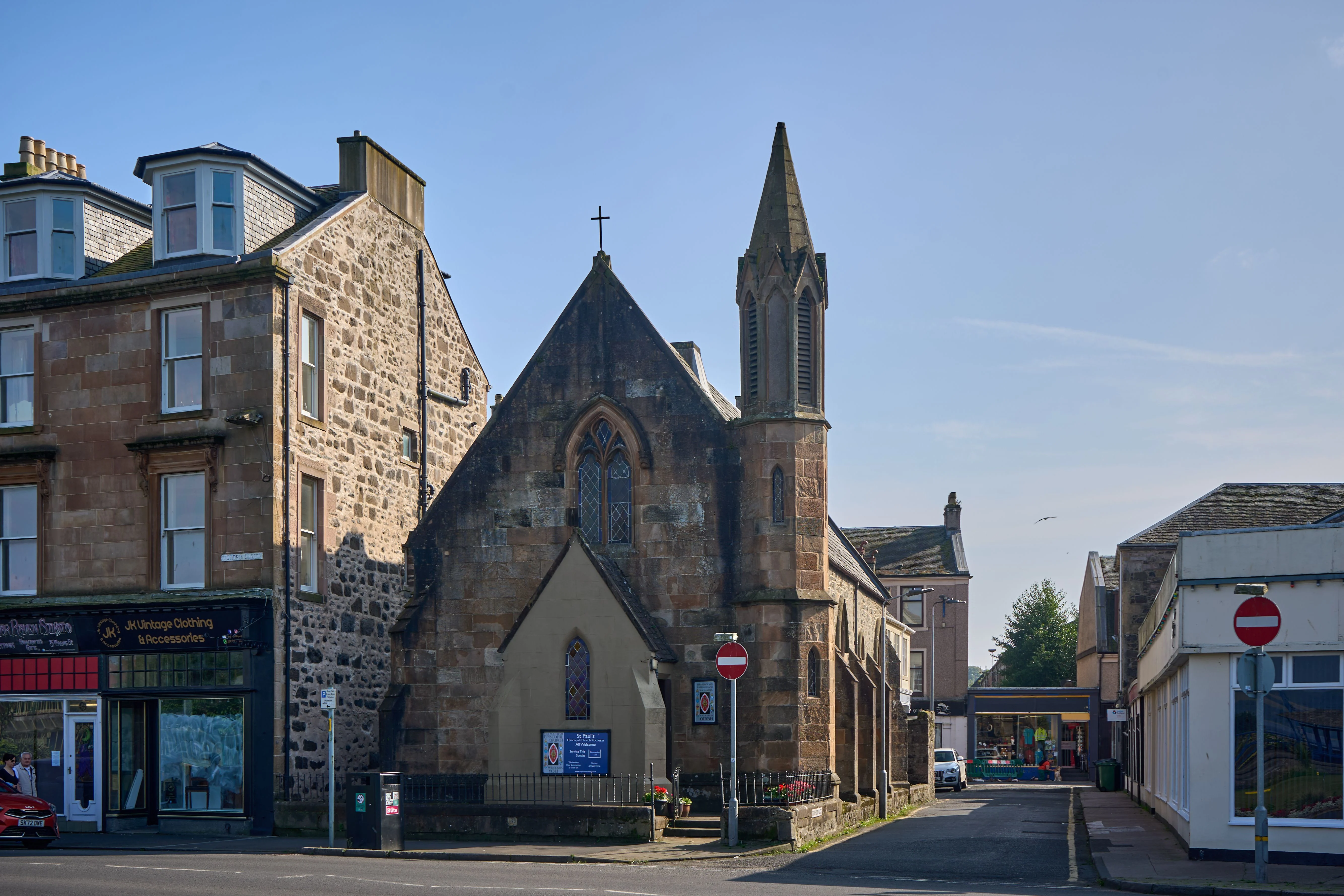 Historic Scottish village street with stone church and traditional buildings under clear sky