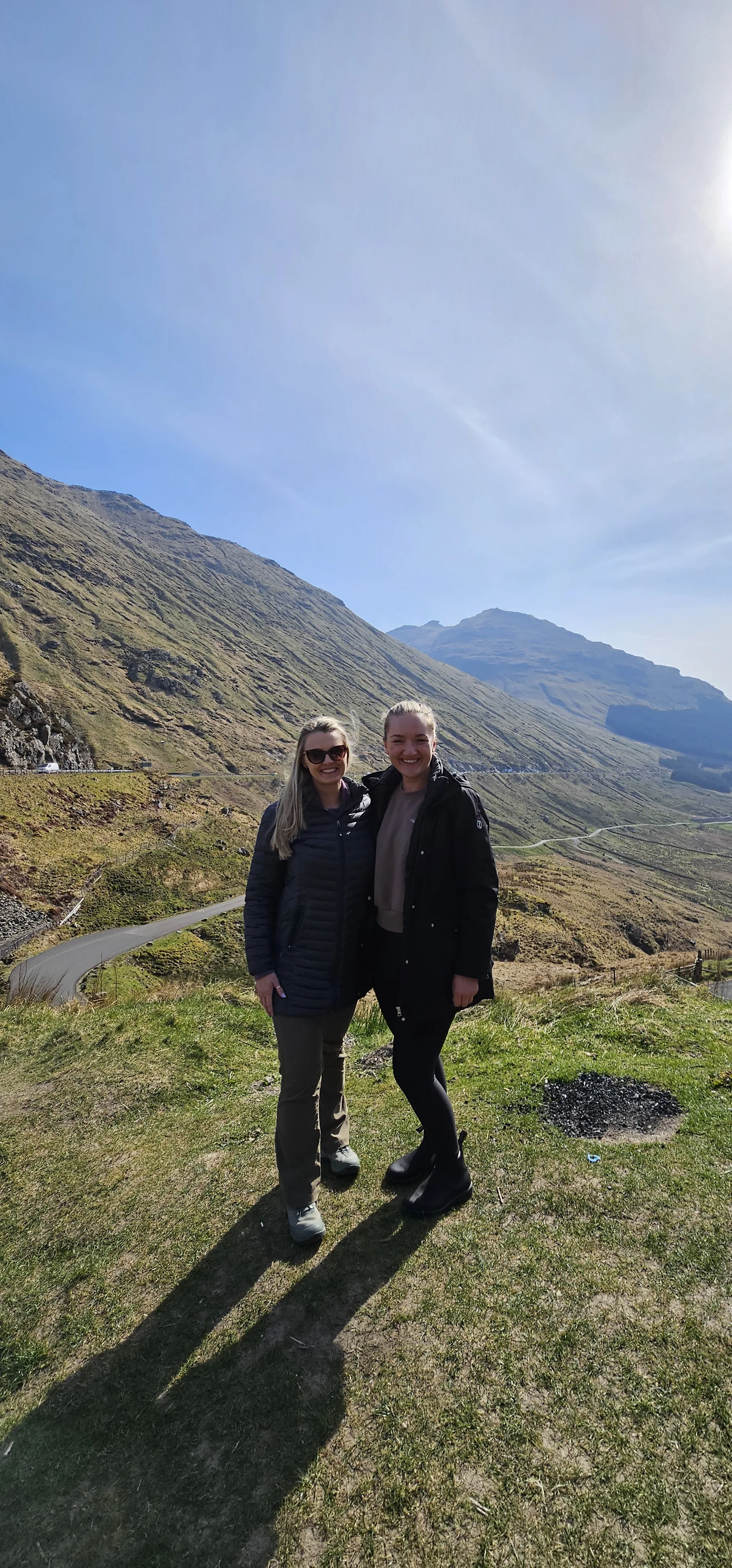 Two women smiling on a Scottish hillside with mountains in the background