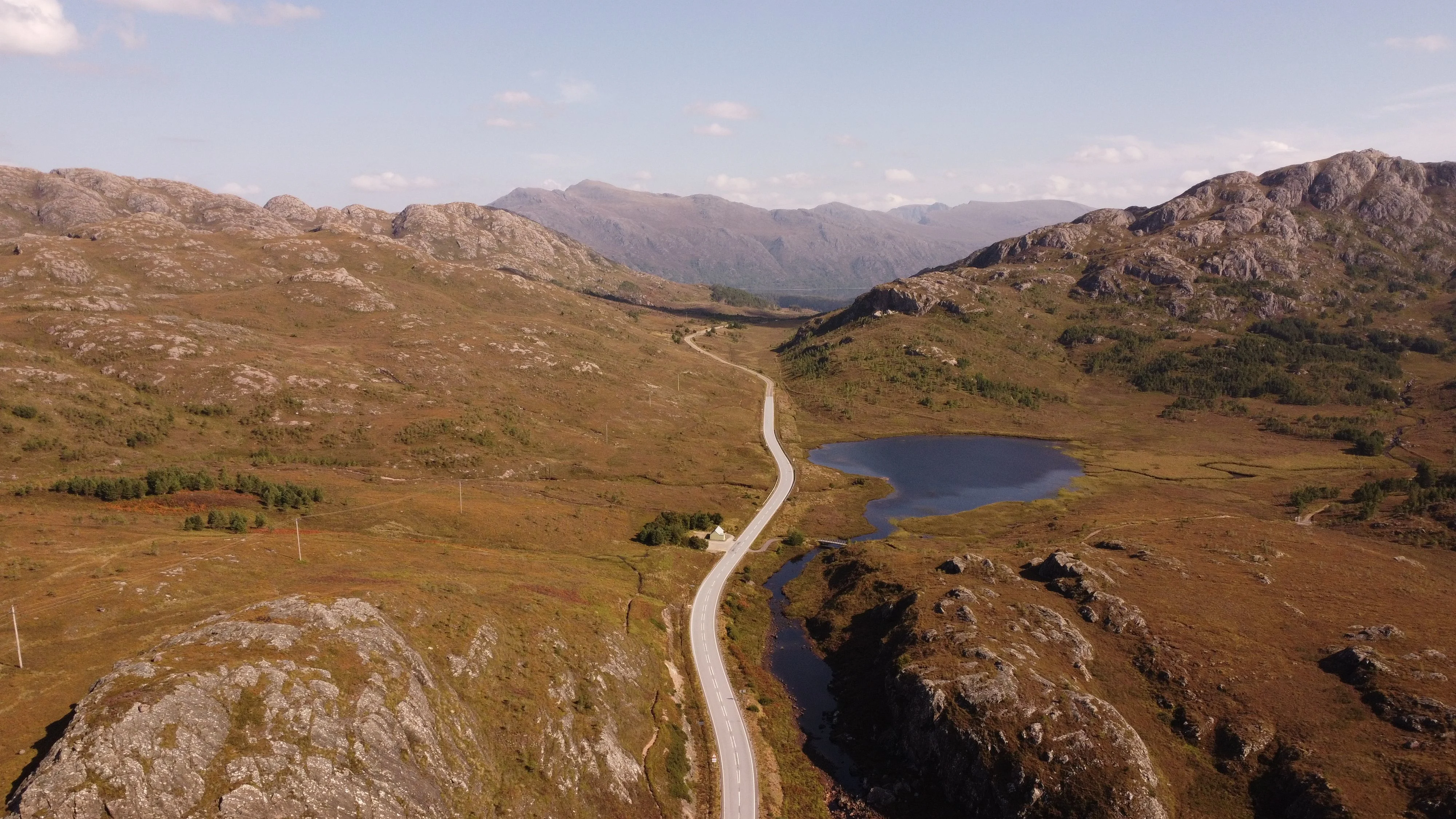 Winding road through Scottish Highlands with mountains, loch and moorland