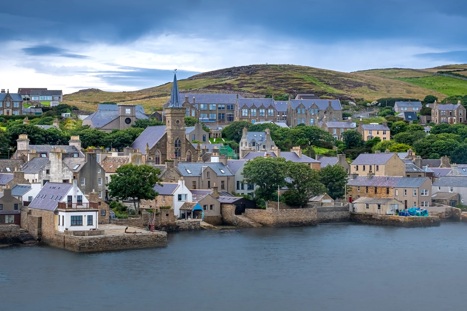 Picturesque Scottish coastal village with stone houses, church, and green hills