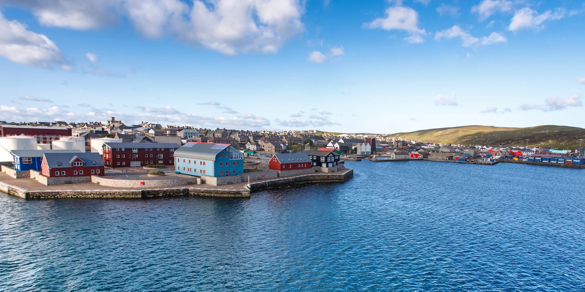 Colorful waterfront buildings in a Scottish harbor town under blue sky