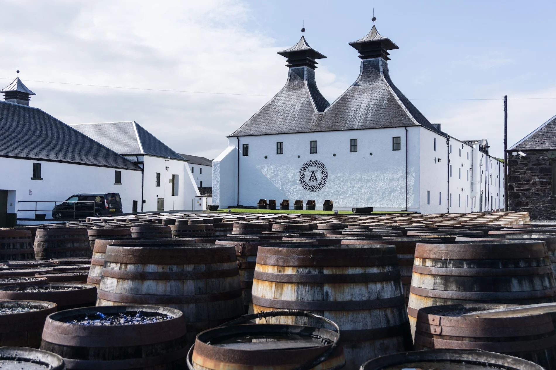 Scottish whisky distillery with pagoda roofs and wooden barrels in courtyard