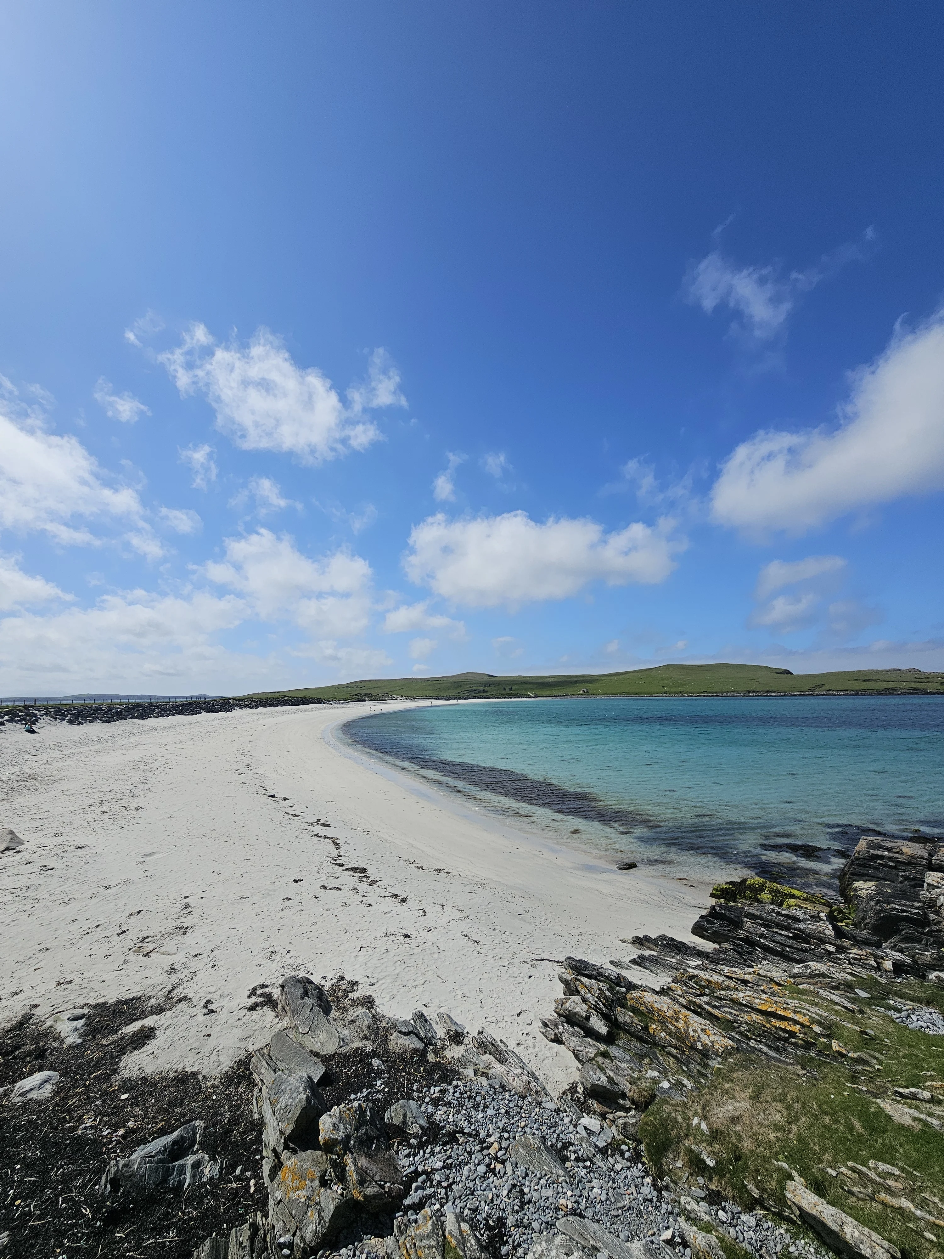 Pristine Scottish beach with turquoise water and green hills beyond