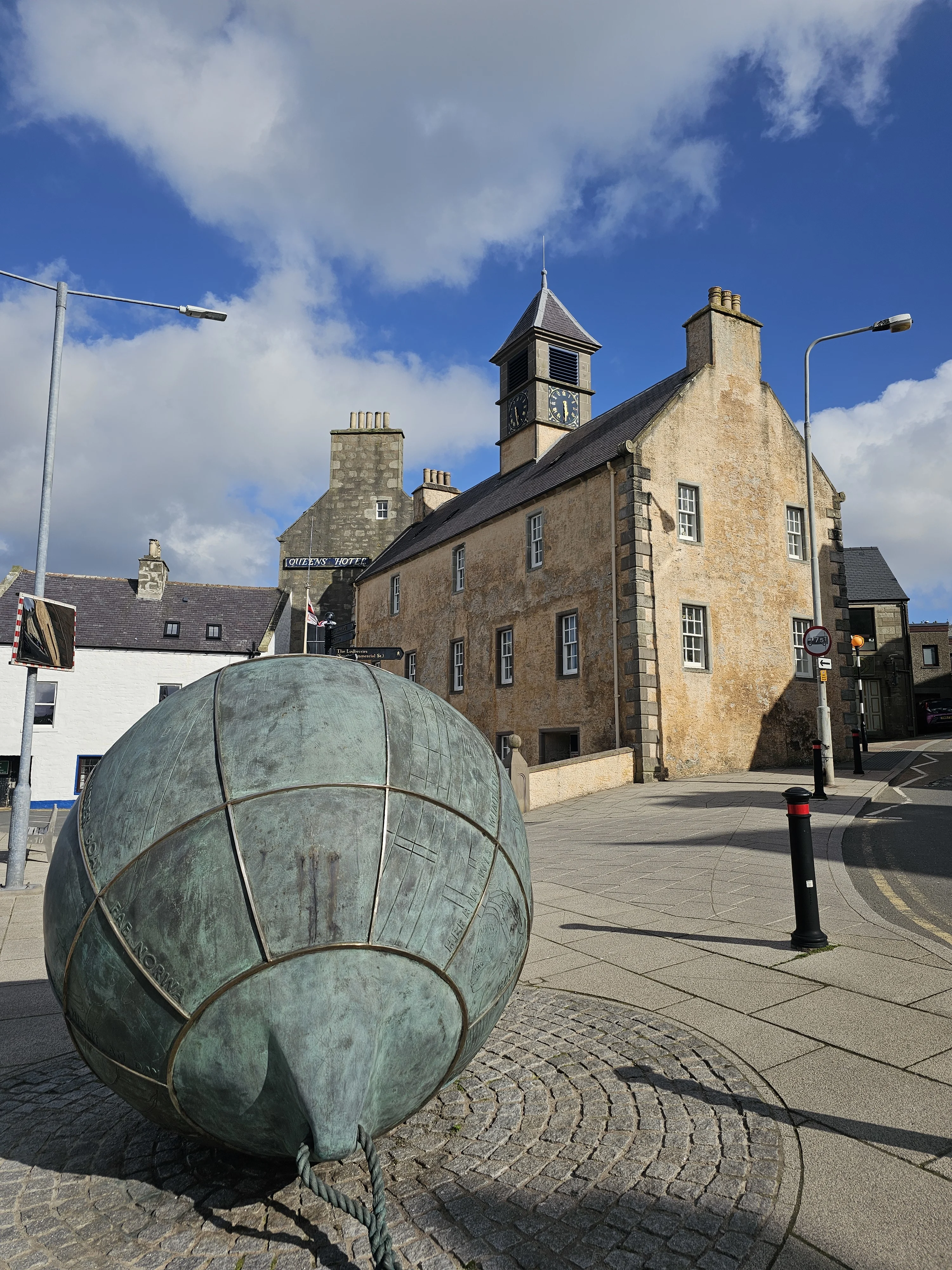 Scottish village square with stone buildings and bronze sculpture