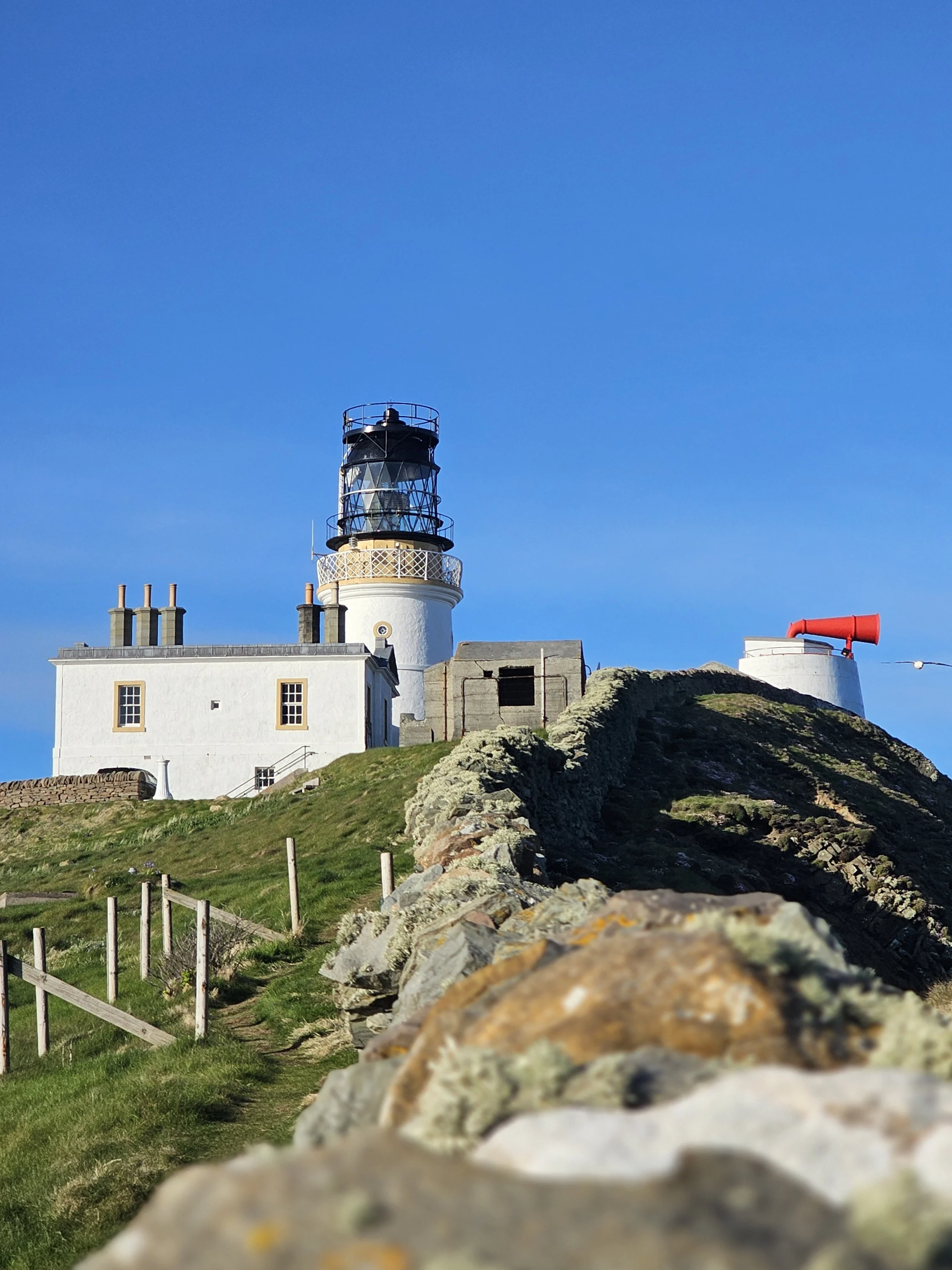 Scottish coastal lighthouse with white keeper's house and rocky headland