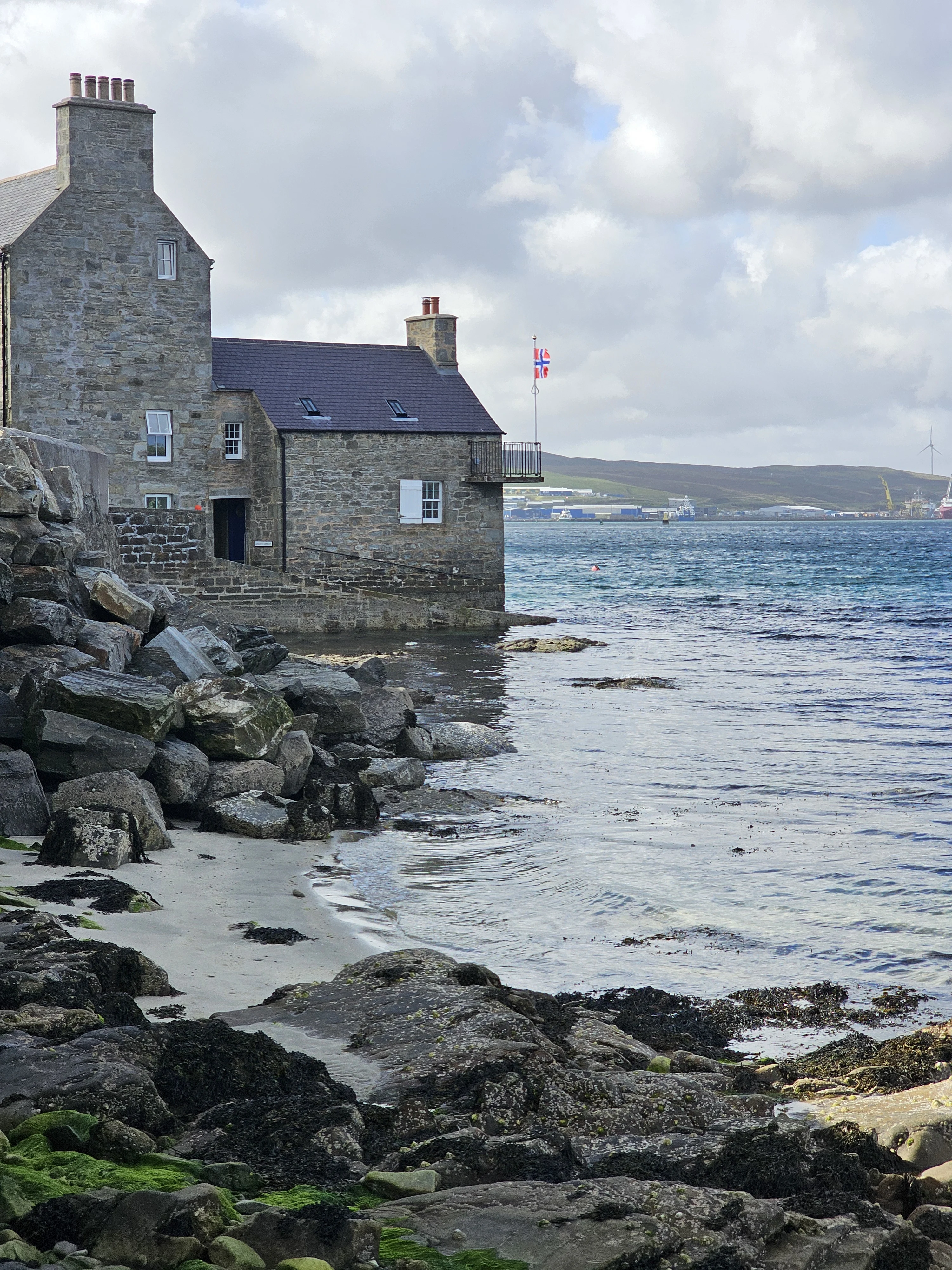 Stone cottages by rocky Scottish coastline with Union Jack flag flying