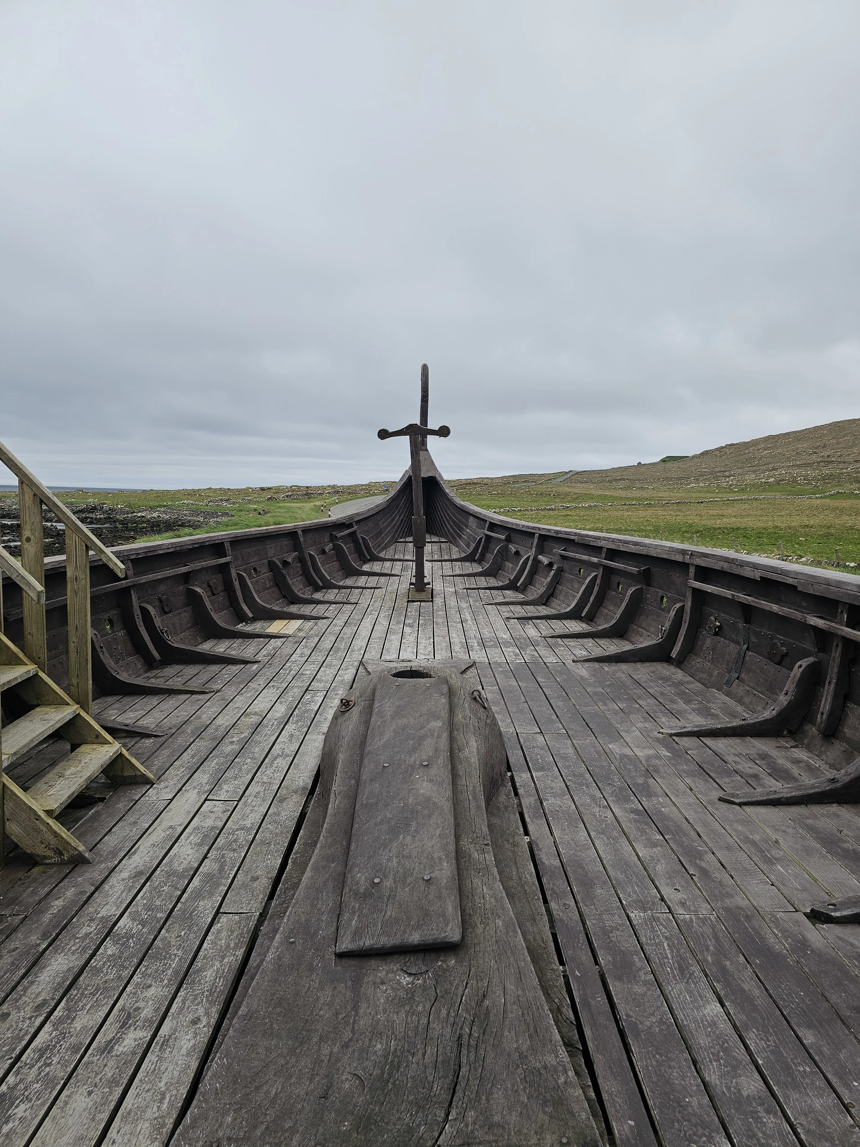 Interior view of a Viking longship replica in Scotland with moorland landscape behind.