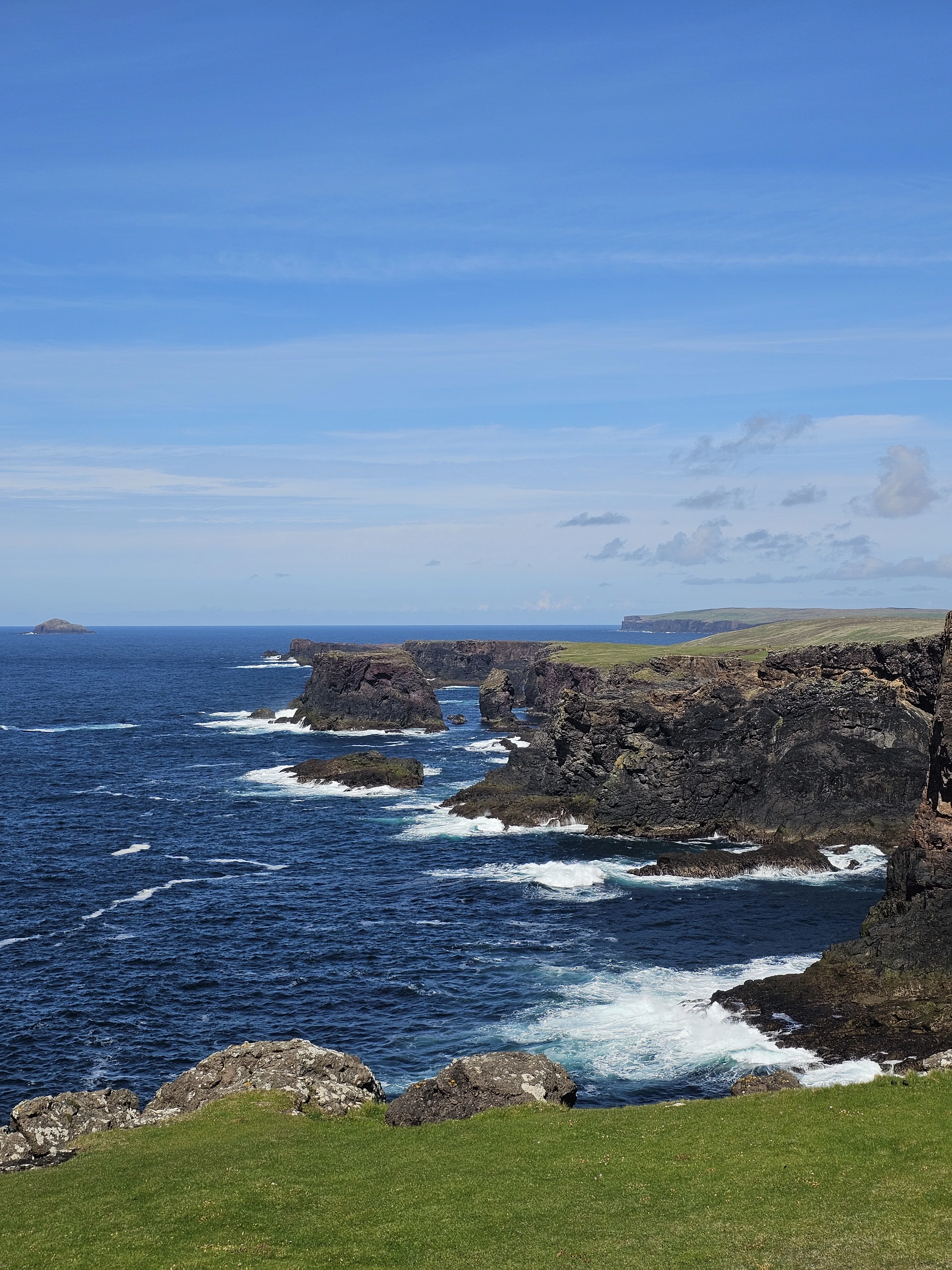 Dramatic Scottish coastal cliffs with rocky stacks and crashing waves below