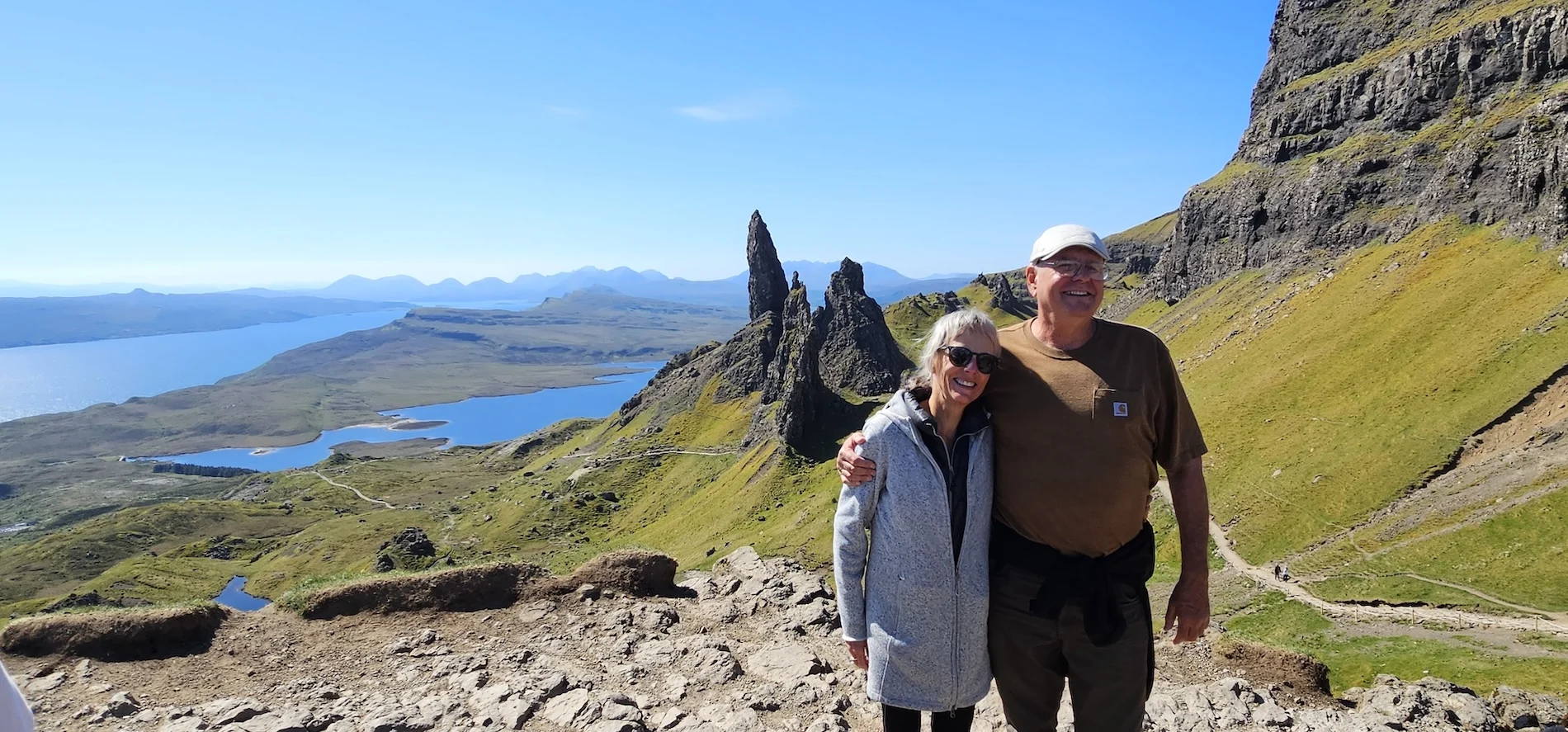 Couple at Old Man of Storr viewpoint overlooking Scottish Highlands and lochs