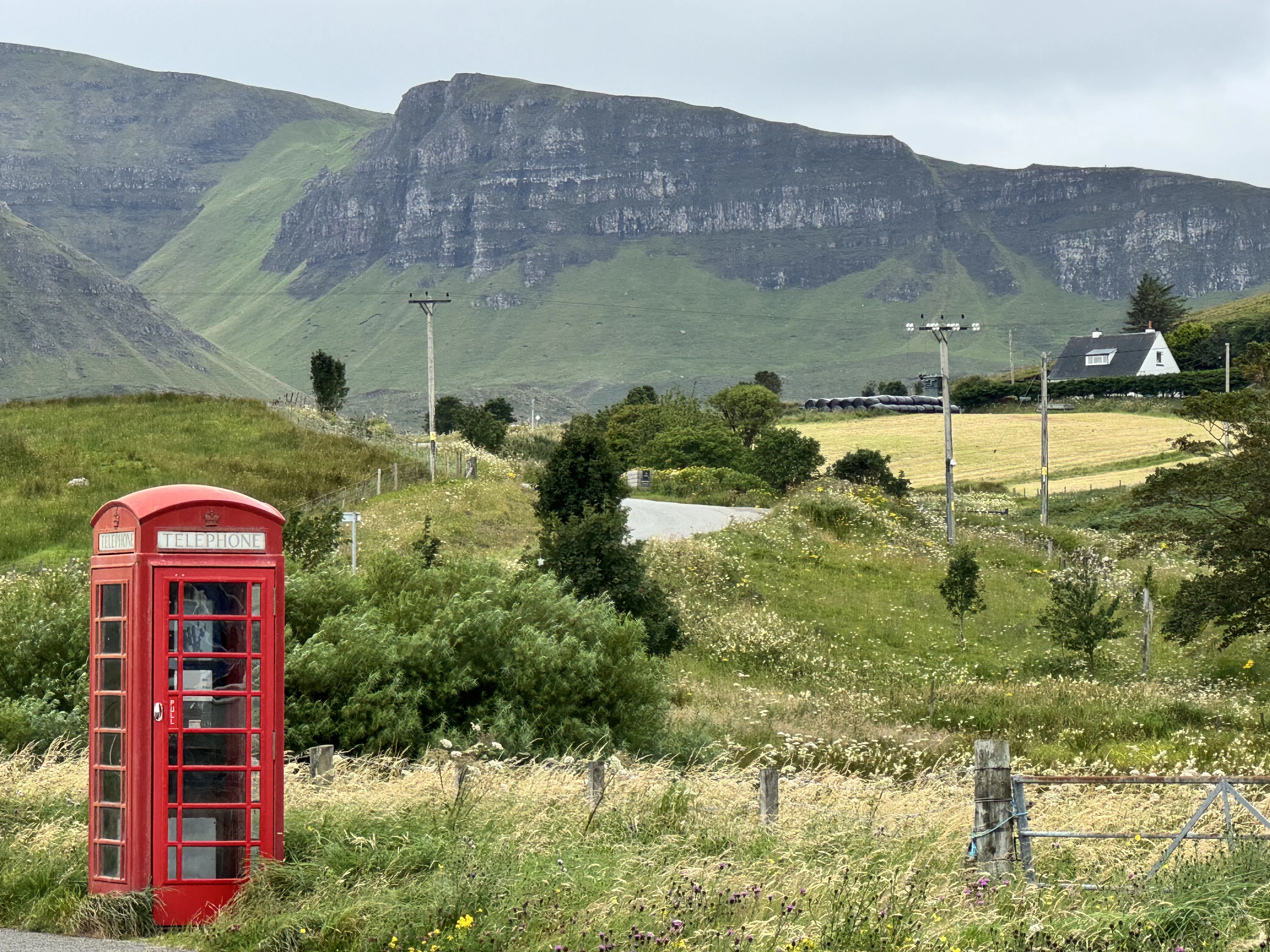 Red British telephone box in Scottish Highland valley with mountains