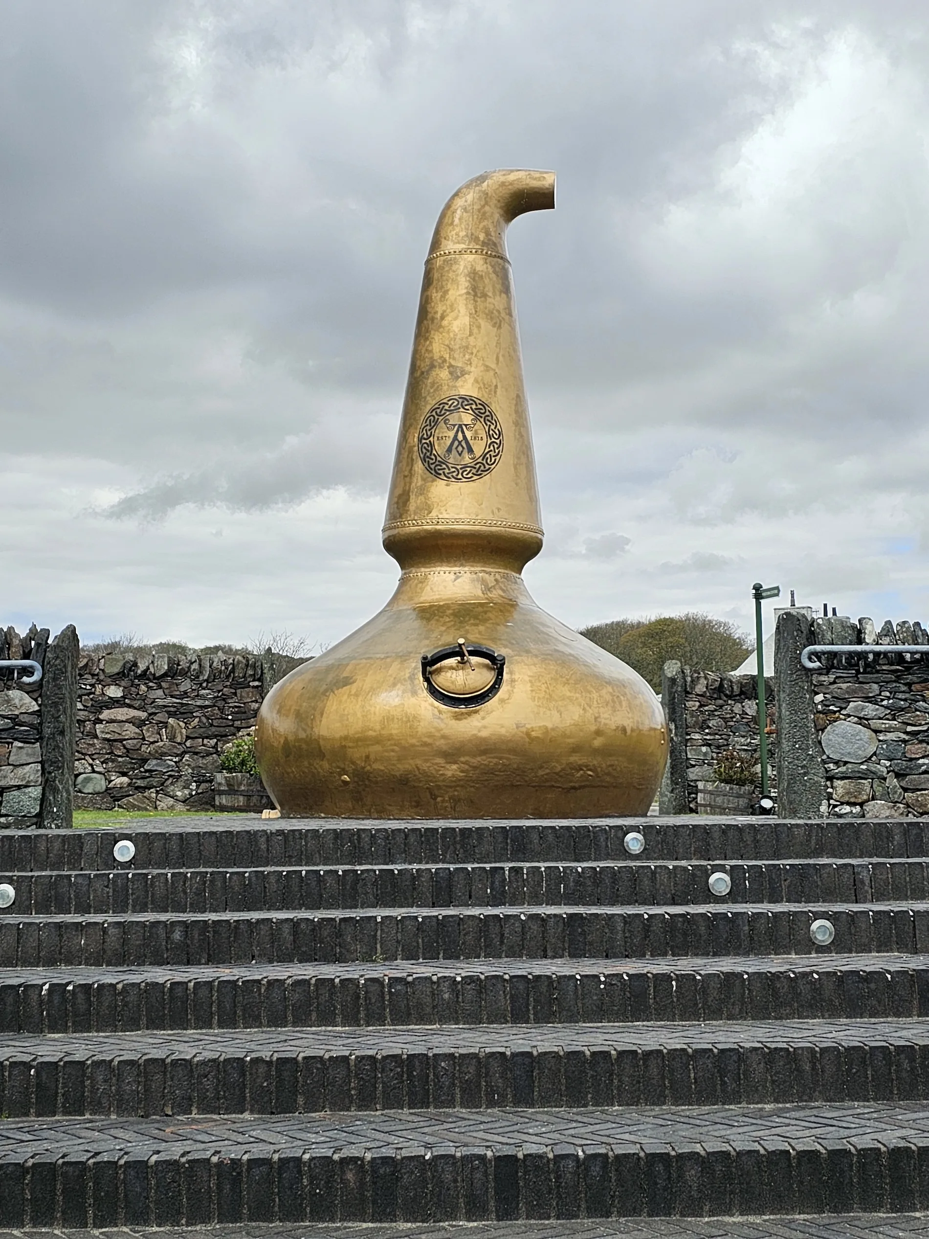 Large golden whisky still sculpture with Masonic symbol at Scottish distillery