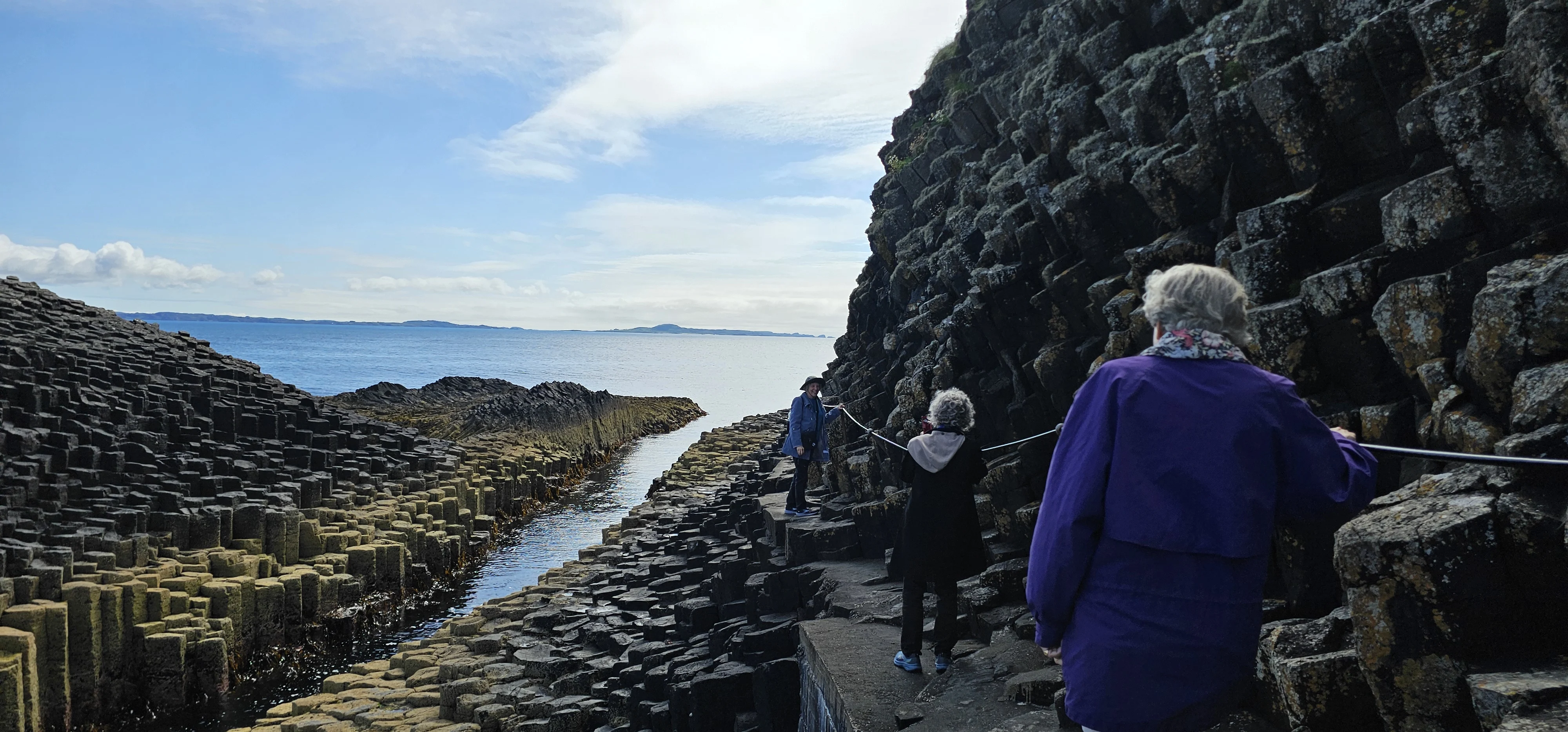 Visitors explore hexagonal basalt columns at Scotland's Giant's Causeway coastal formation.