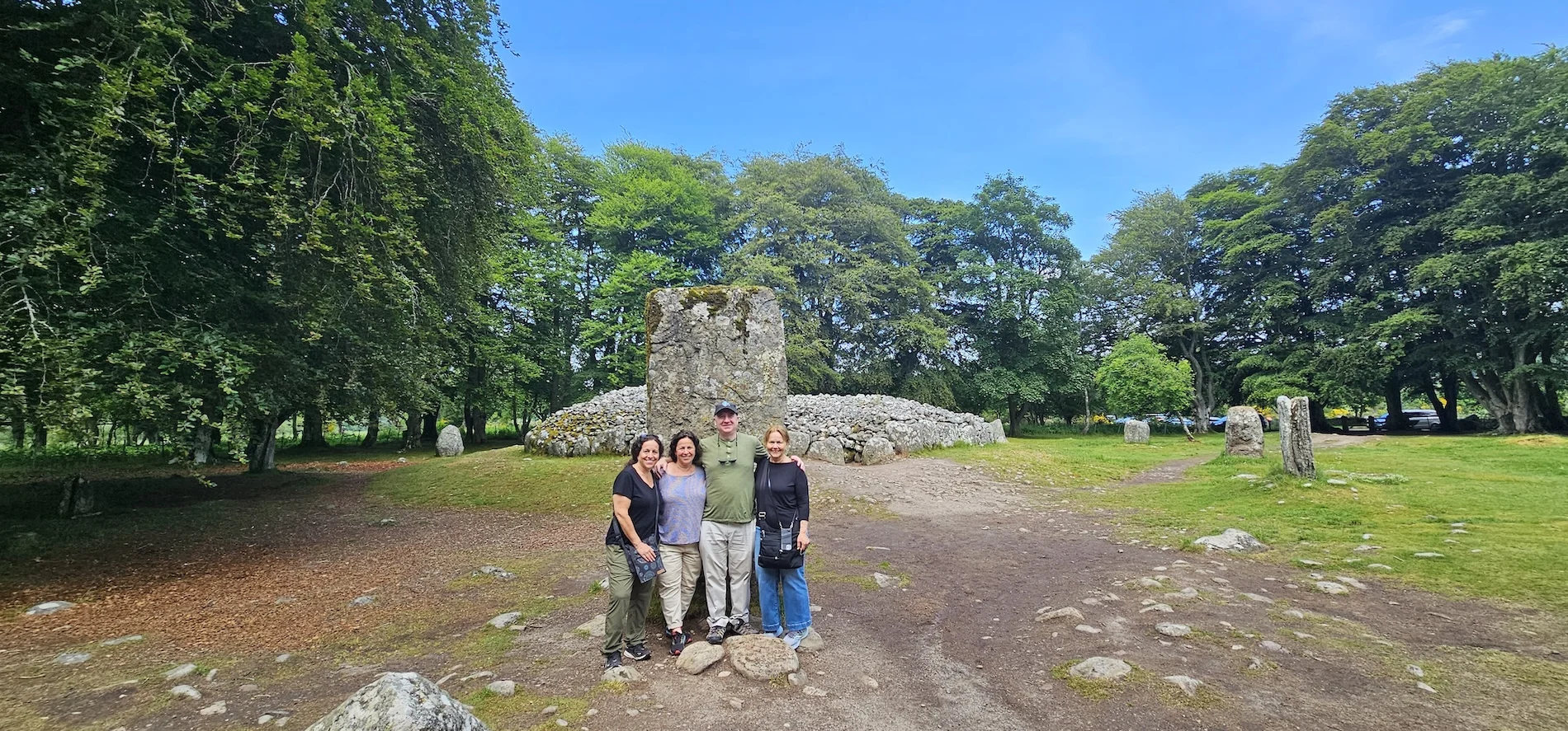 Group of four tourists posing at ancient Scottish stone circle ruins