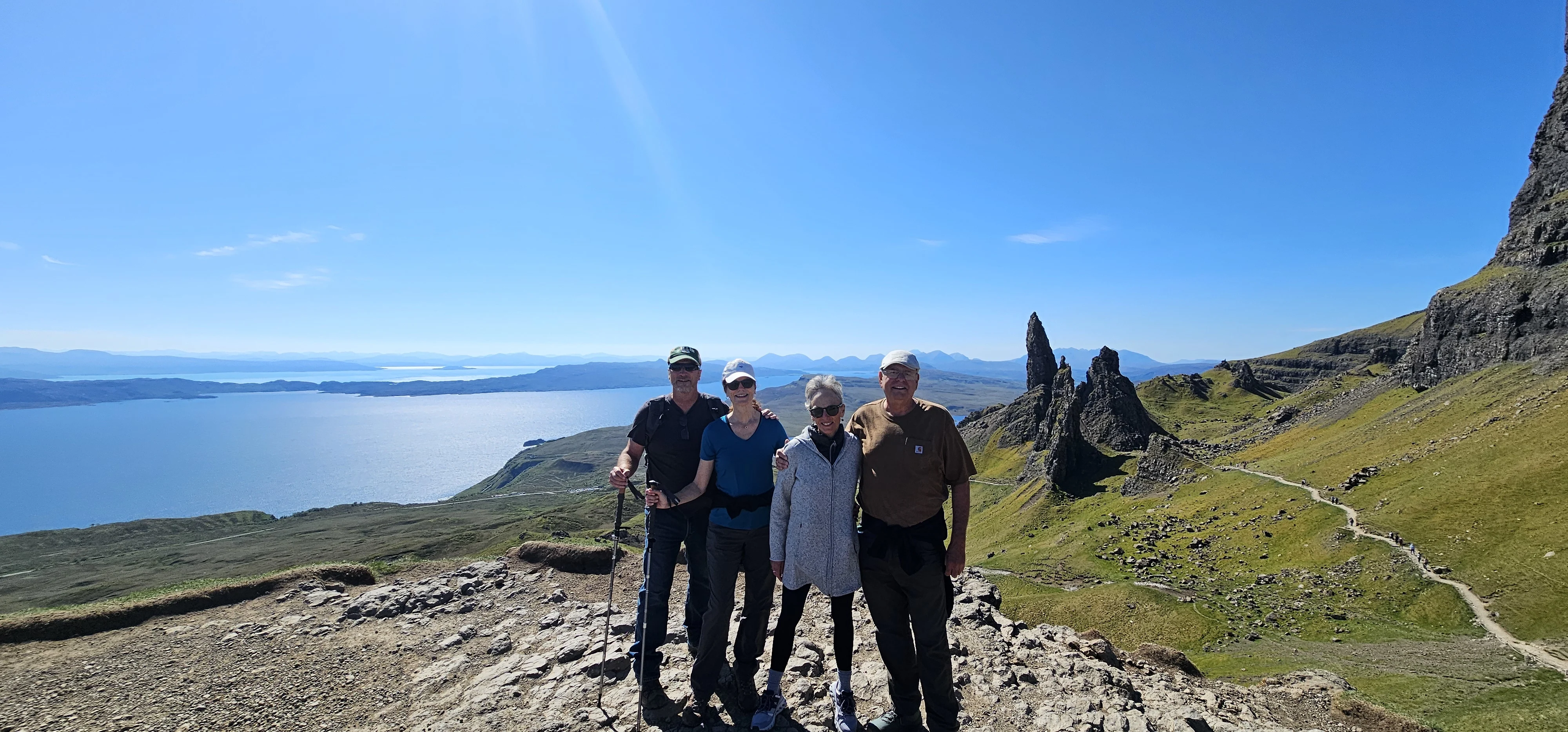 Group of four hikers posing on Scottish mountain overlooking sea and islands