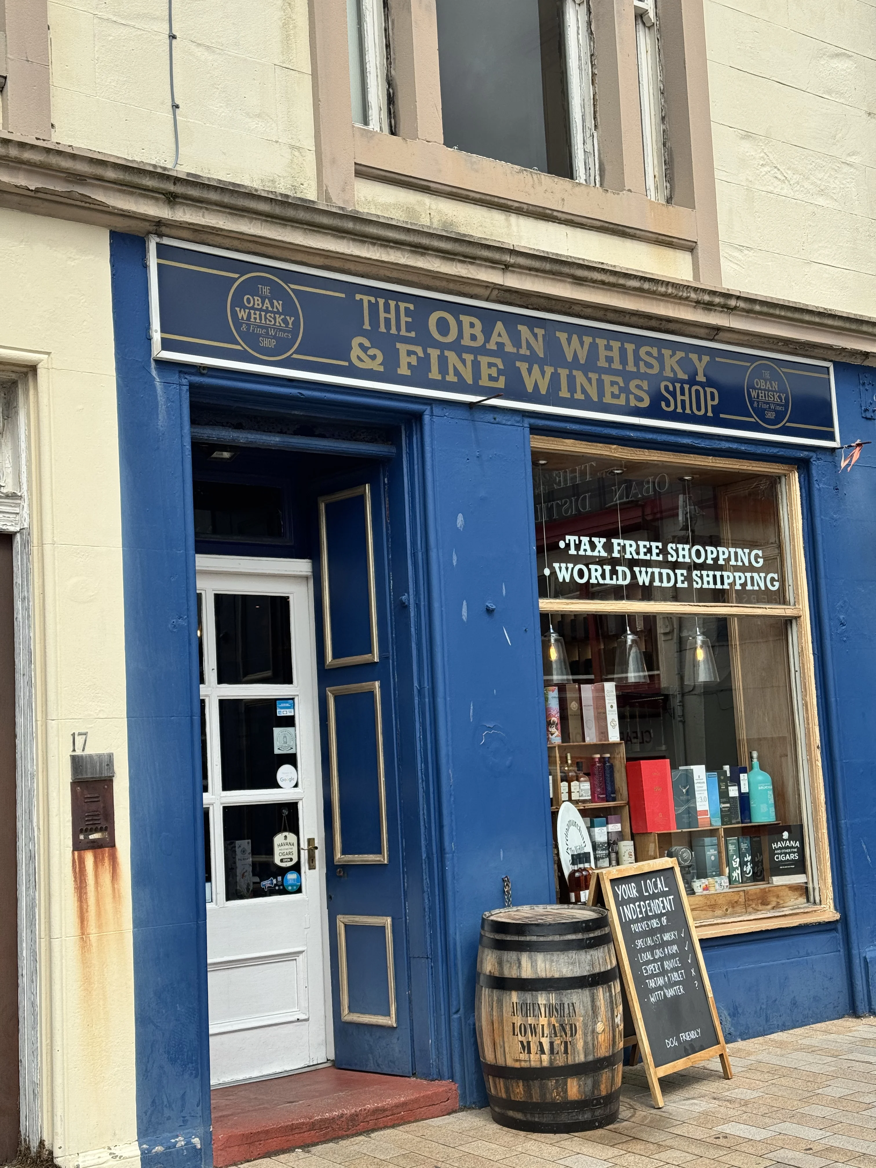 The Oban Whisky and Fine Wines Shop storefront with blue facade and barrel