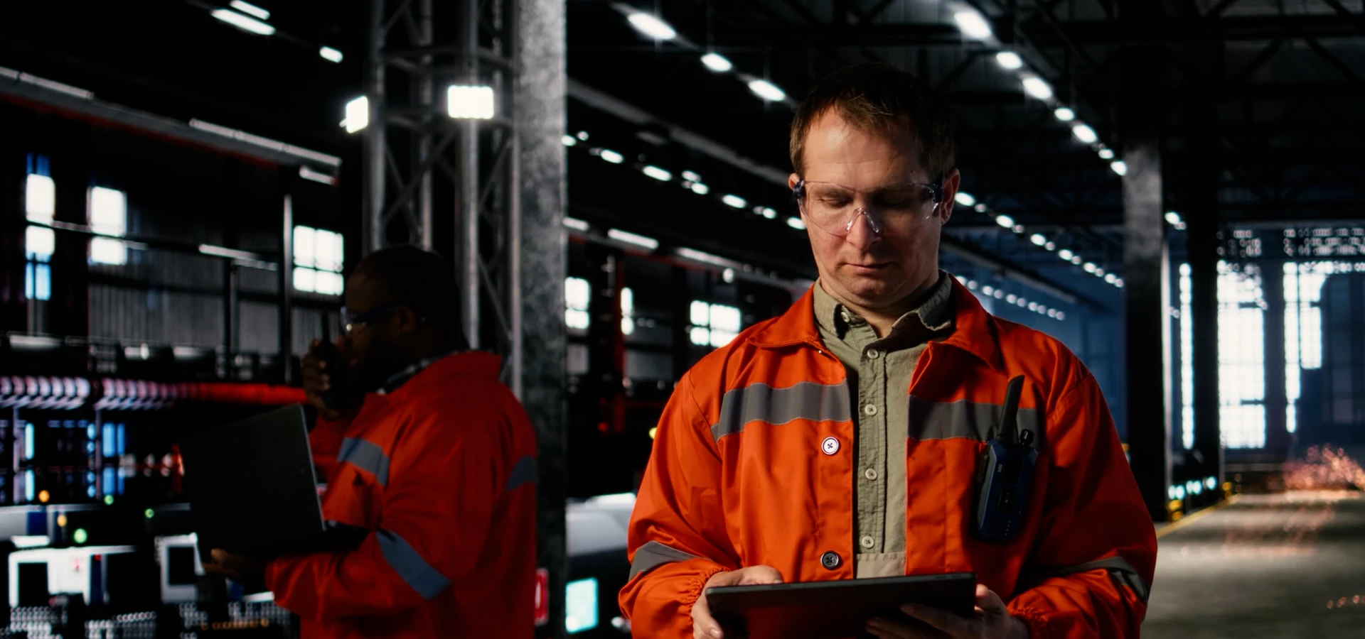 a person in an industrial work suit looking at a tablet computer