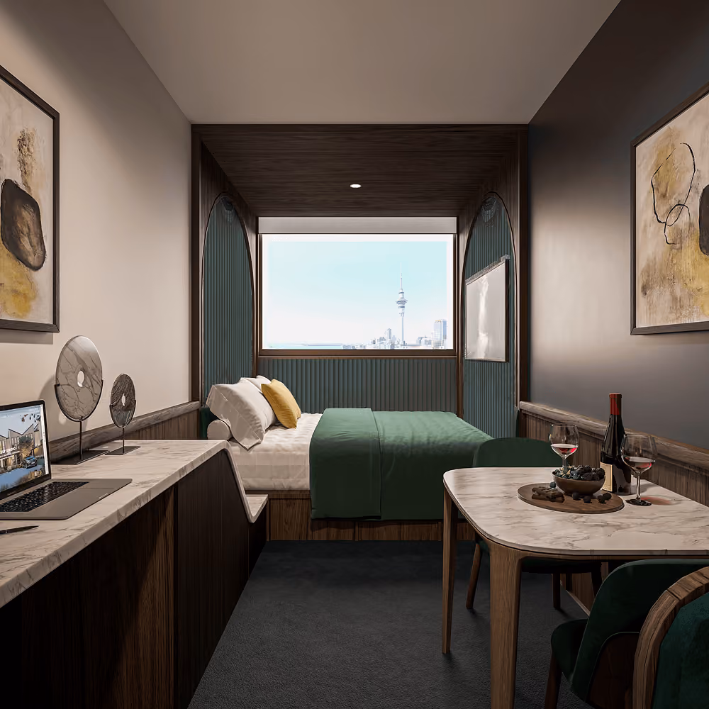 Modern hotel room with green bedding, work desk, dining area, and window view of city skyline.