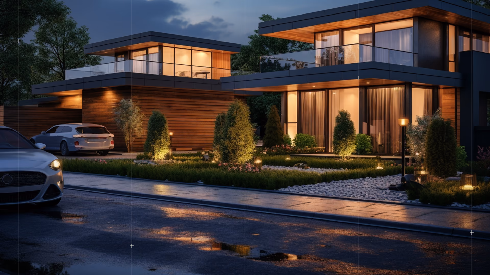 Modern two-story house at dusk with large windows, wood siding, lit garden, and parked cars on wet street.