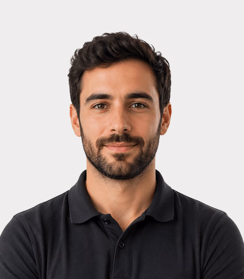 Mann mit dunklem Haar und Vollbart, trägt ein schwarzes Poloshirt vor neutralem Hintergrund.