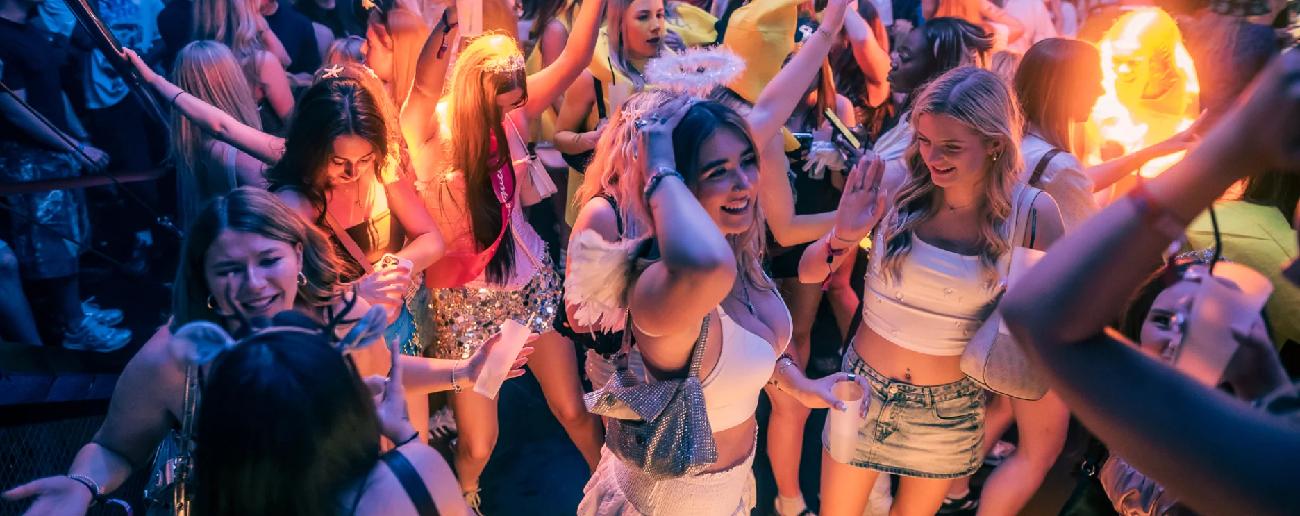 Festival crowd cheering together with flares lit up.