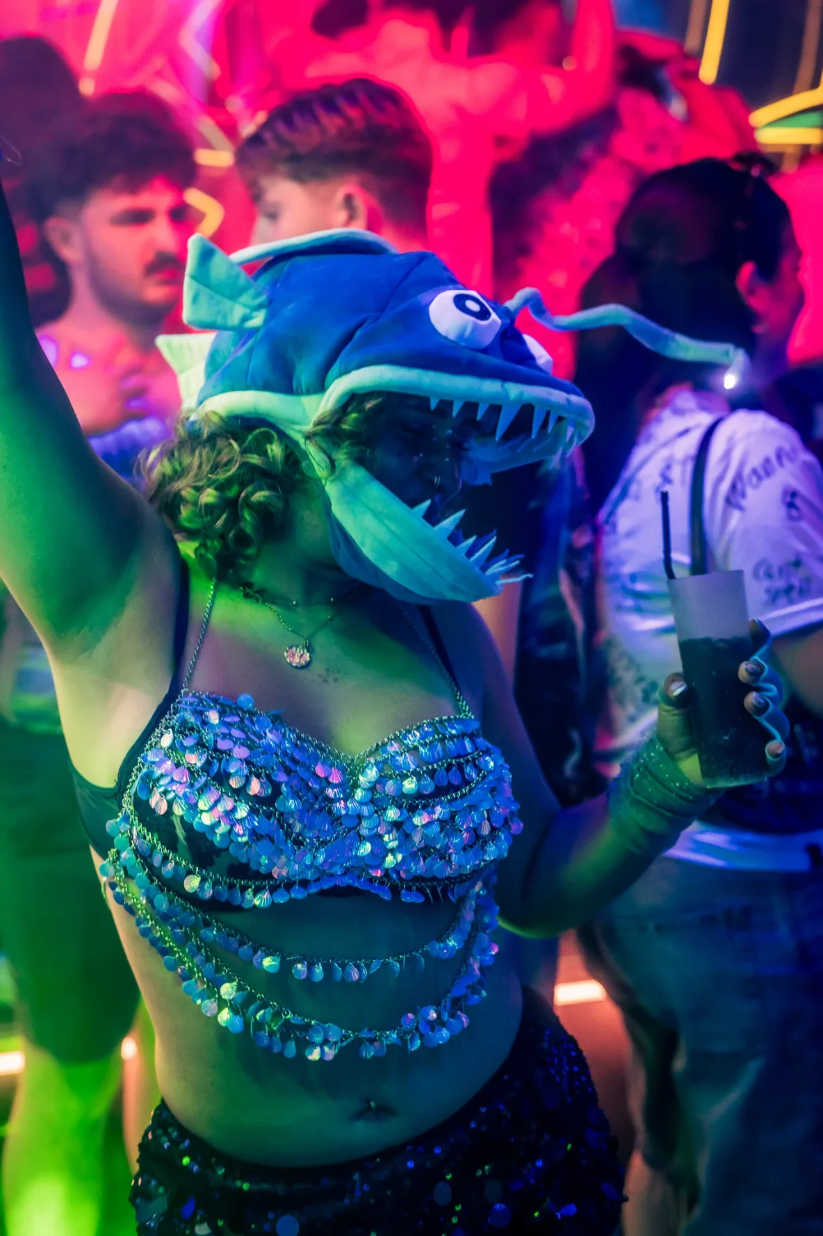 Person wearing a novelty fish hat while dancing at a nightclub.