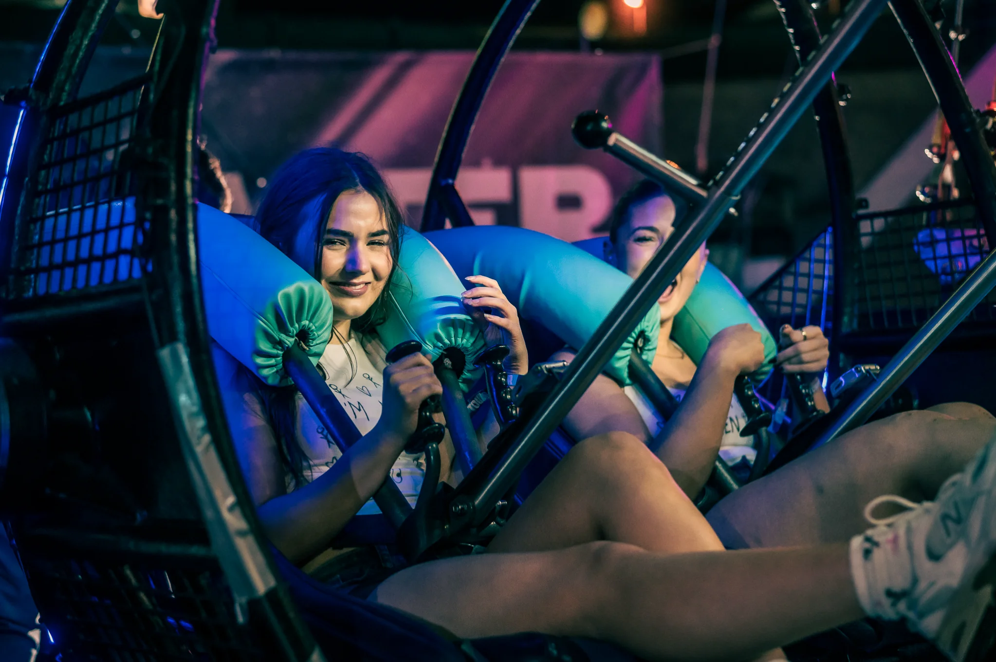Young women laughing together on an amusement park ride during a group trip.