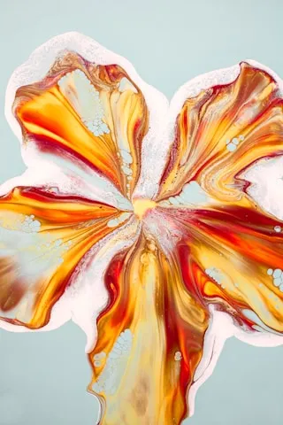 Abstract fluid art resembling a flower with swirling orange, red, and white paint on light blue background.