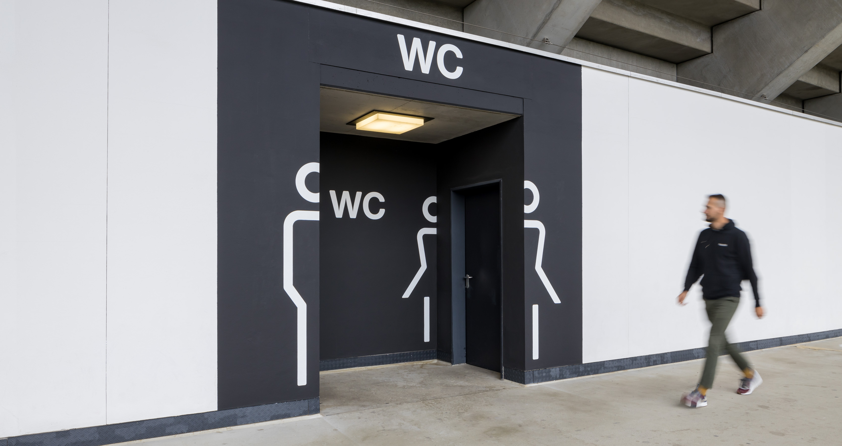 Eingang zu den Toiletten des Deutschen Bank Parks mit einer kreativen Wanddarstellung der WC-Icons