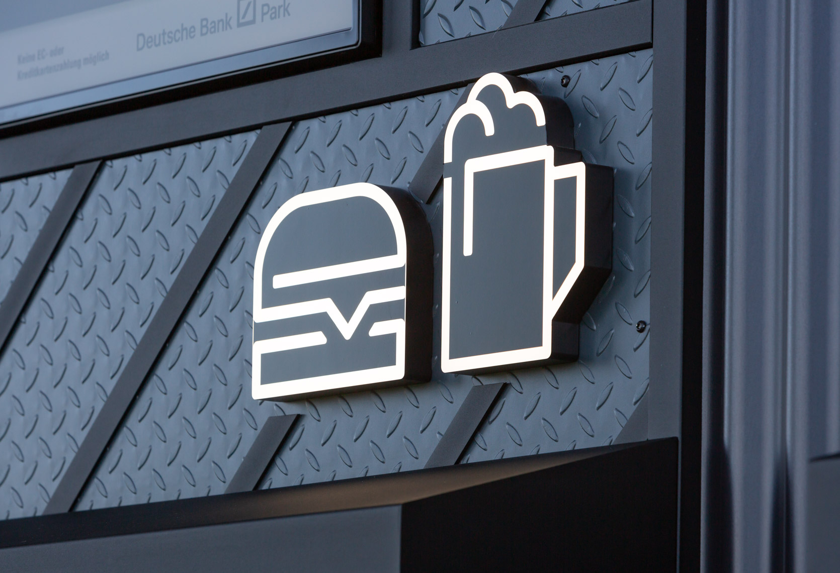 Darstellung von Food-Icons über der Theke eines Würstchenstandes im Deutsche Bank Park