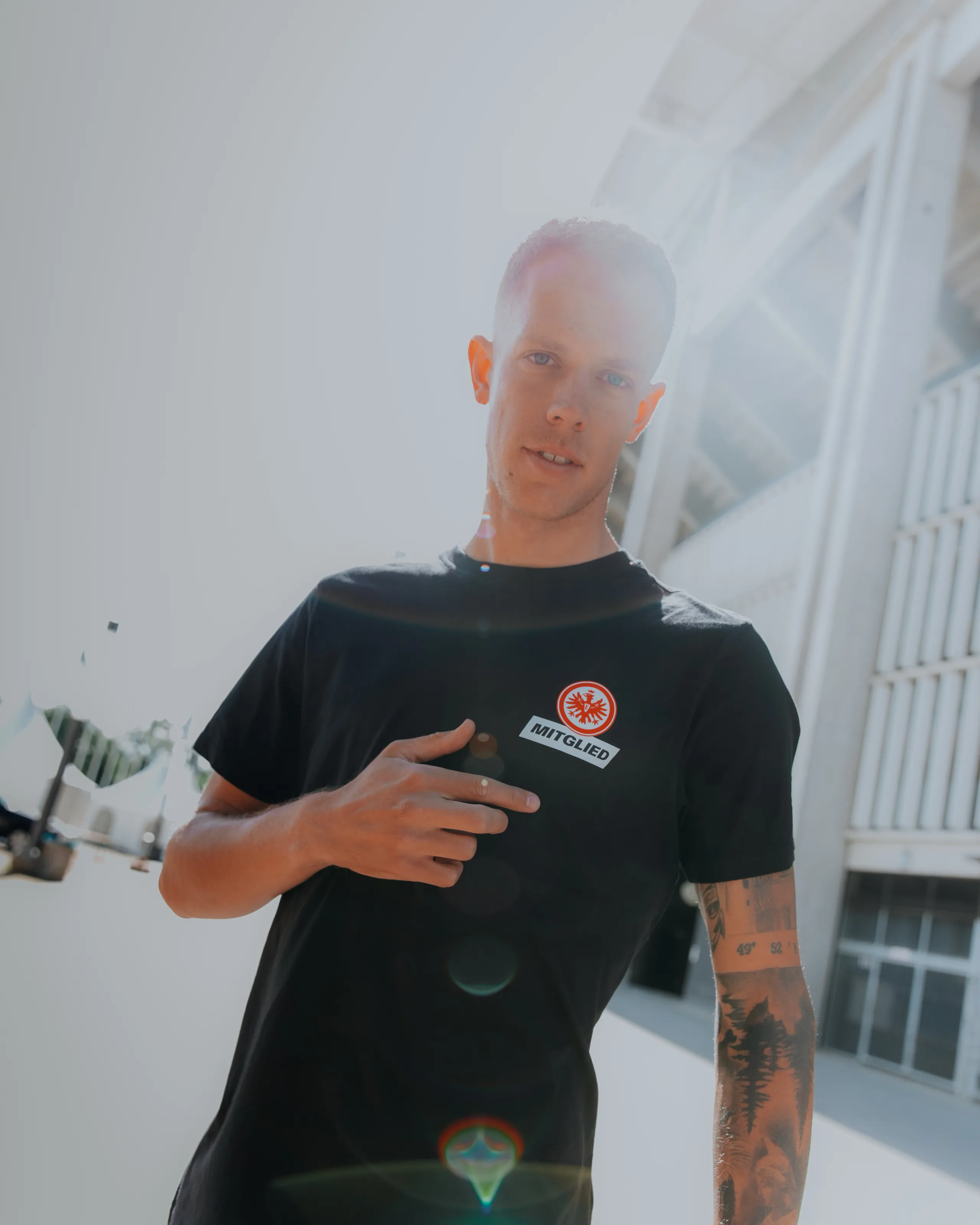 Ein Mann trägt ein schwarzes T-Shirt mit einem Mitglieder-Wappen der Eintracht Frankfurt.