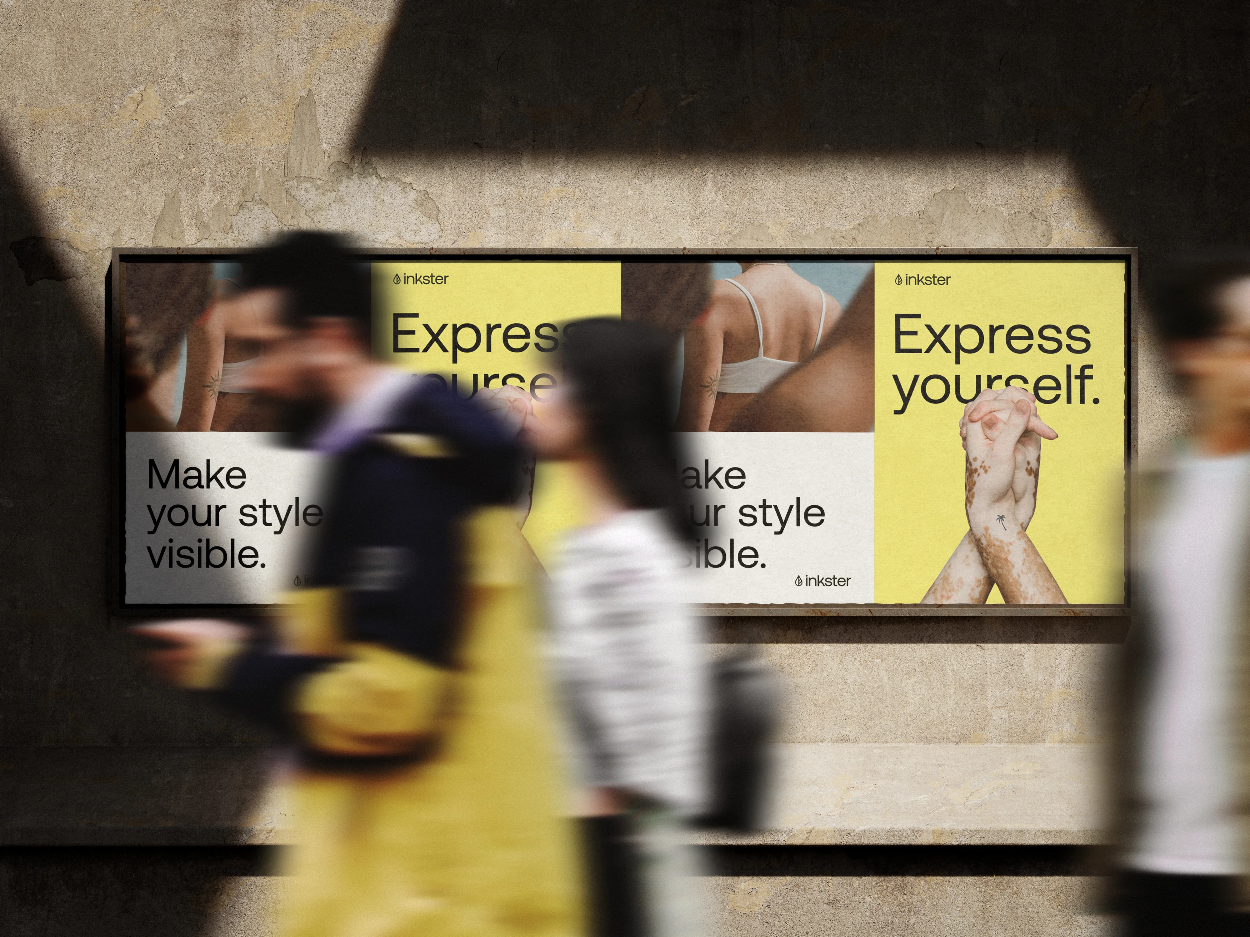 Menschen, die vor einer Plakatwand gehen. Die Plakate zeigen verschiedene Tattoos auf verschiedenen Körperteilen und lauten: "Make your style visible." und „Express yourself.".