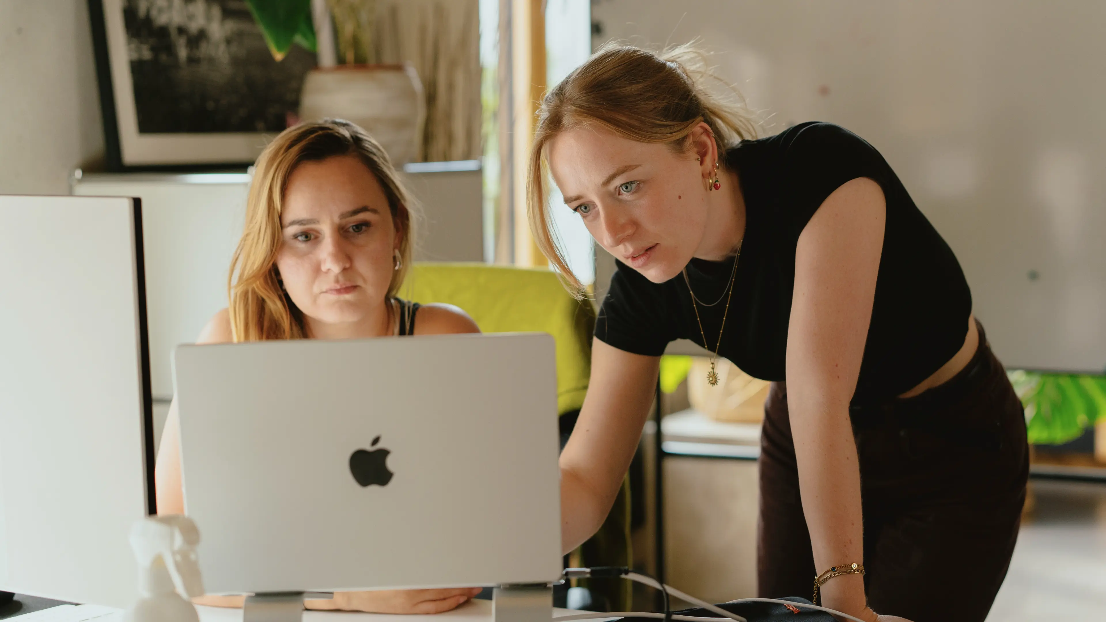 Zwei Frauen schauen in einem Büro auf einen Laptop-Bildschirm.