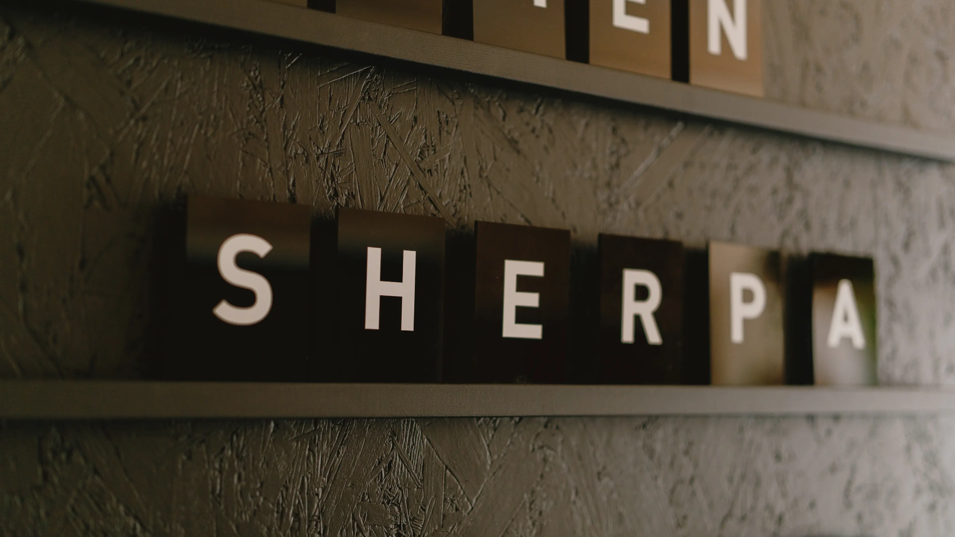 Ein beleuchteter „SHERPA“-Schriftzug an einer strukturierten Wand, der zu einer größeren Informationstafel gehört.