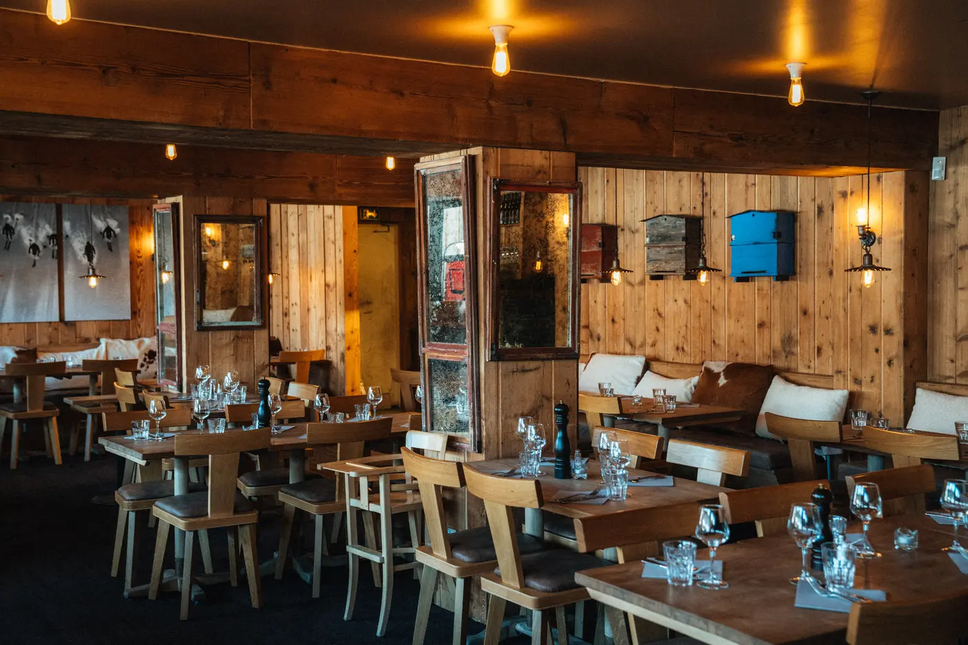 Intérieur de restaurant chaleureux en bois, avec des tables dressées (verres), des chaises et des appliques murales décoratives, restaurant La Brasserie à Avoriaz, Haute-Savoie, France.
