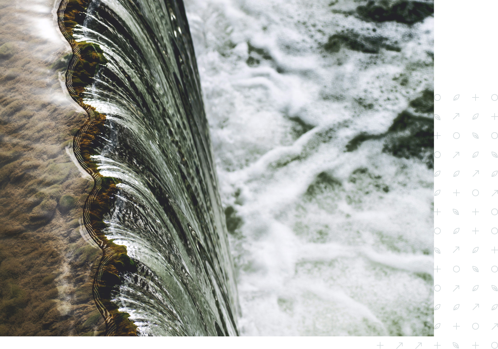 Close-up of water flowing over a curved, scalloped edge into foamy, turbulent water below.
