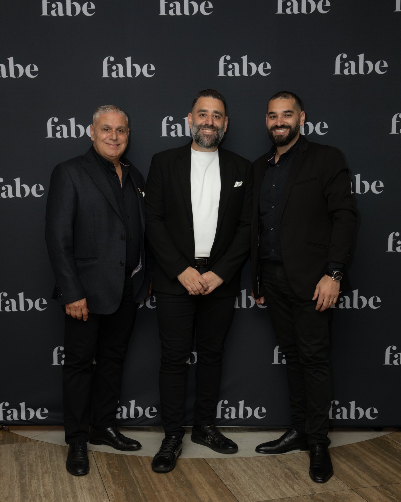 Harry, Roy and Charlie El Hachem standing in front of a FABE media wall