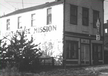 Black and white photo of a two-story building with a sign reading 'Light House Mission'.